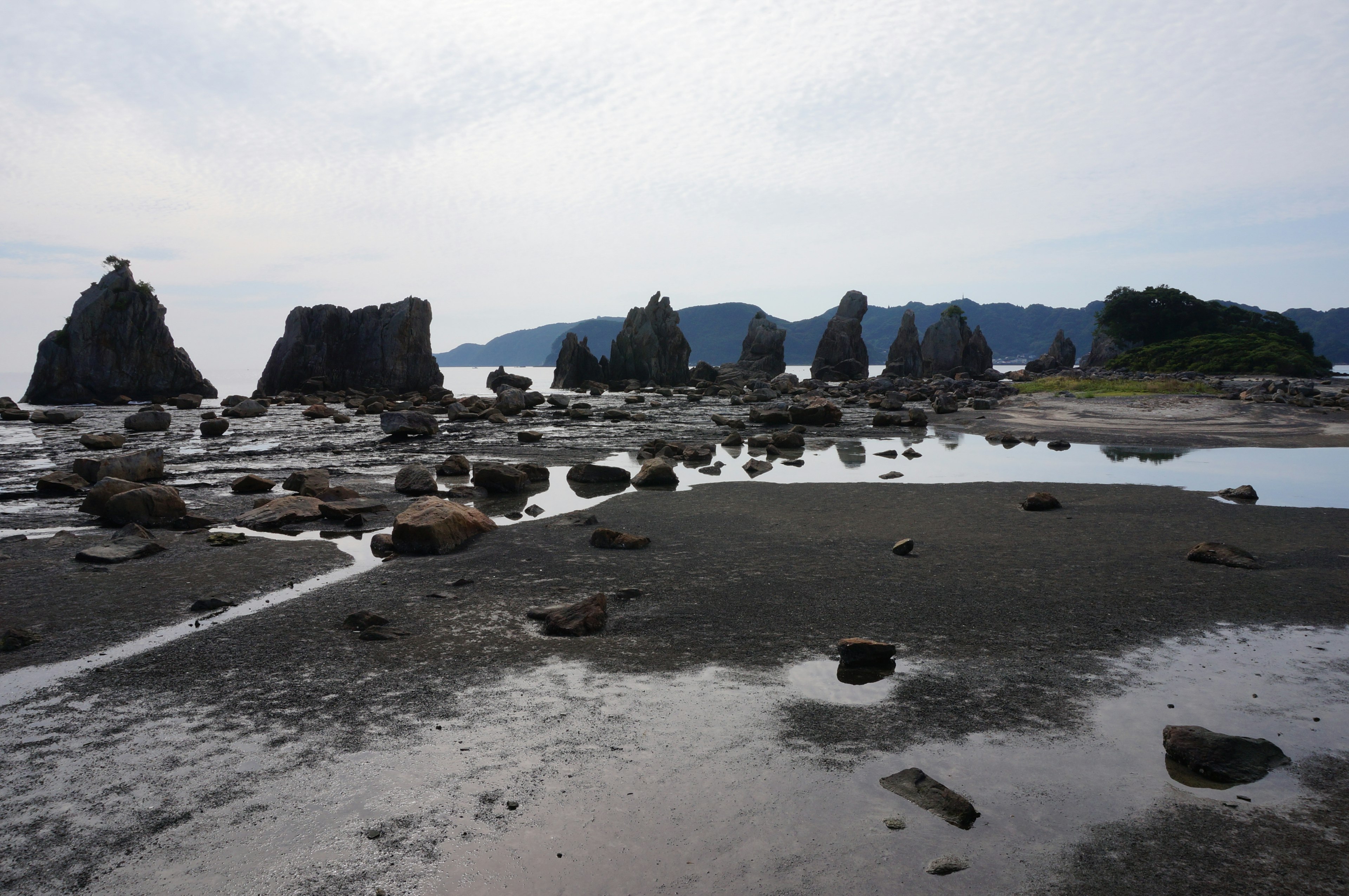 Pemandangan pantai dengan formasi batu dan permukaan air tenang