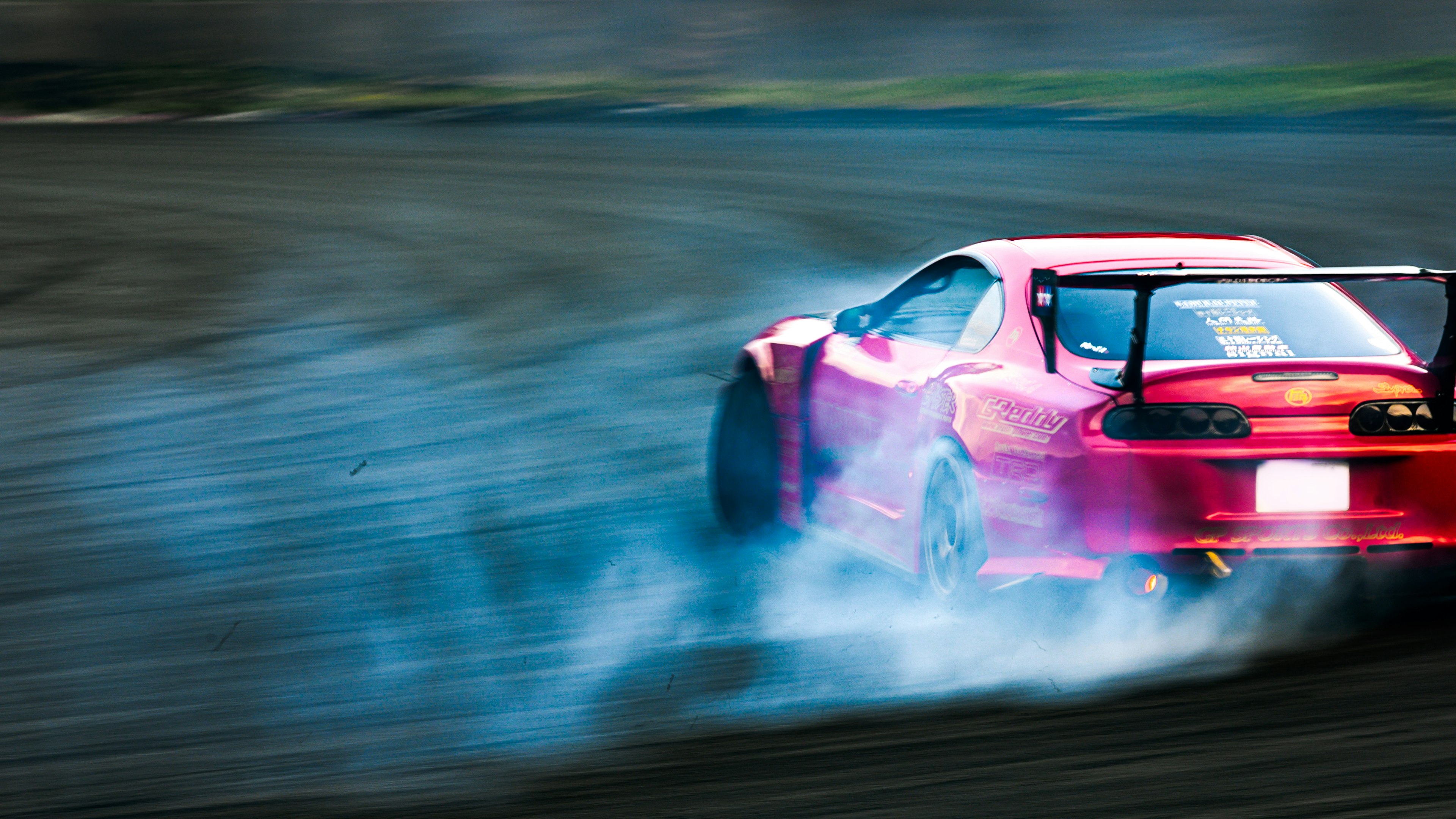 Red sports car drifting with smoke in the background