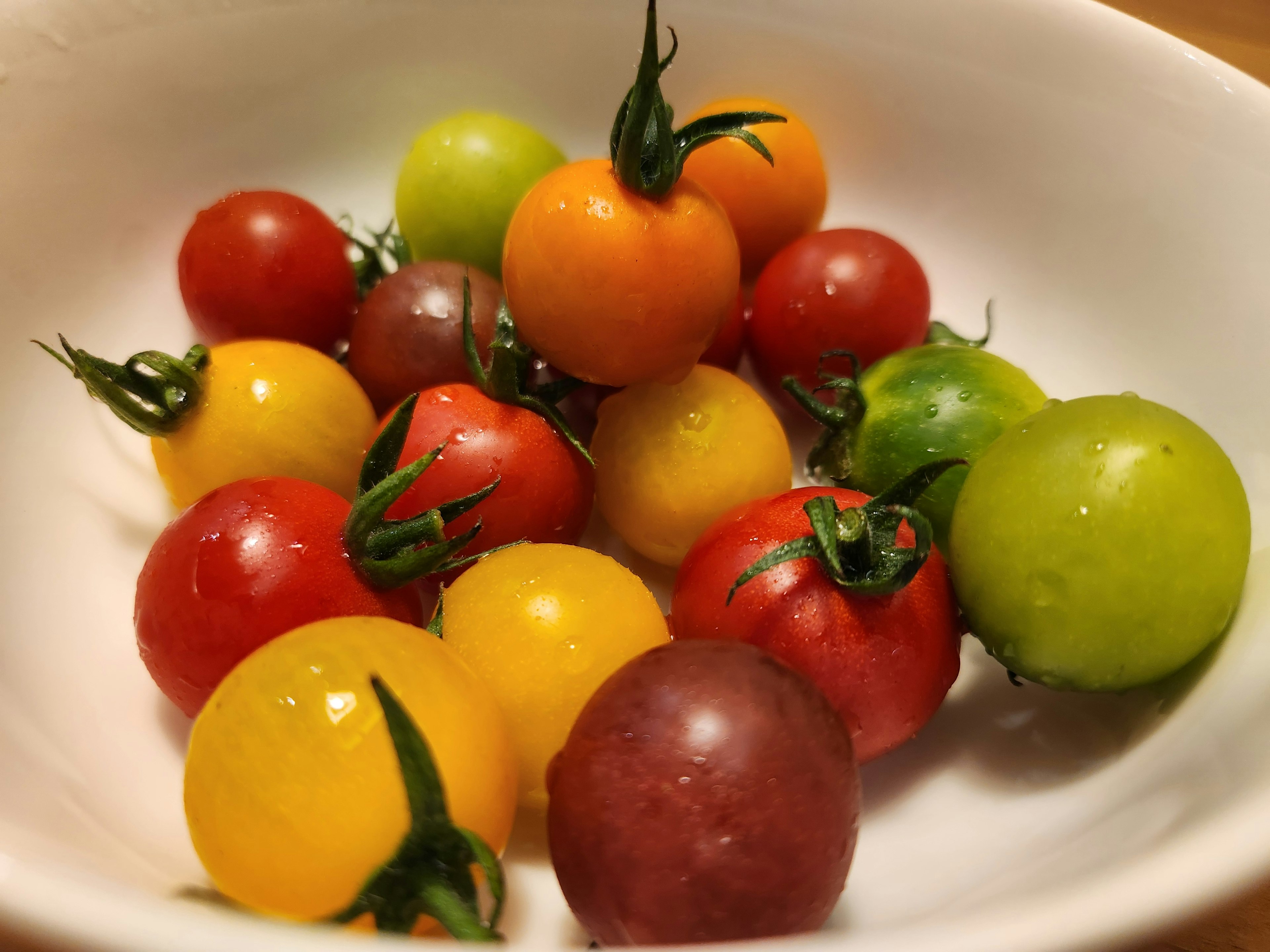 Eine Vielzahl von bunten Kirschtomaten in einer weißen Schüssel