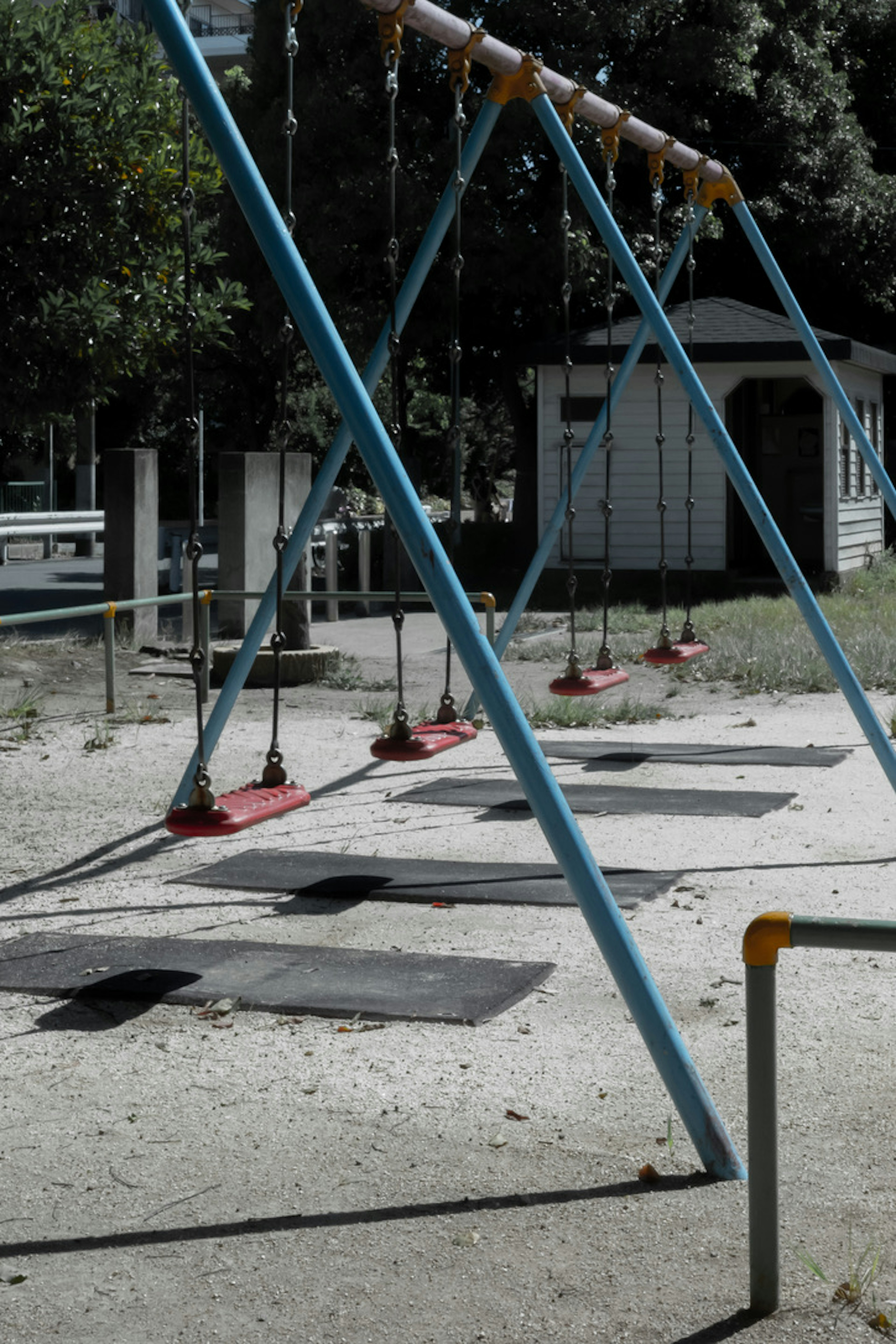 Columpios azules en un parque infantil con suelo de arena