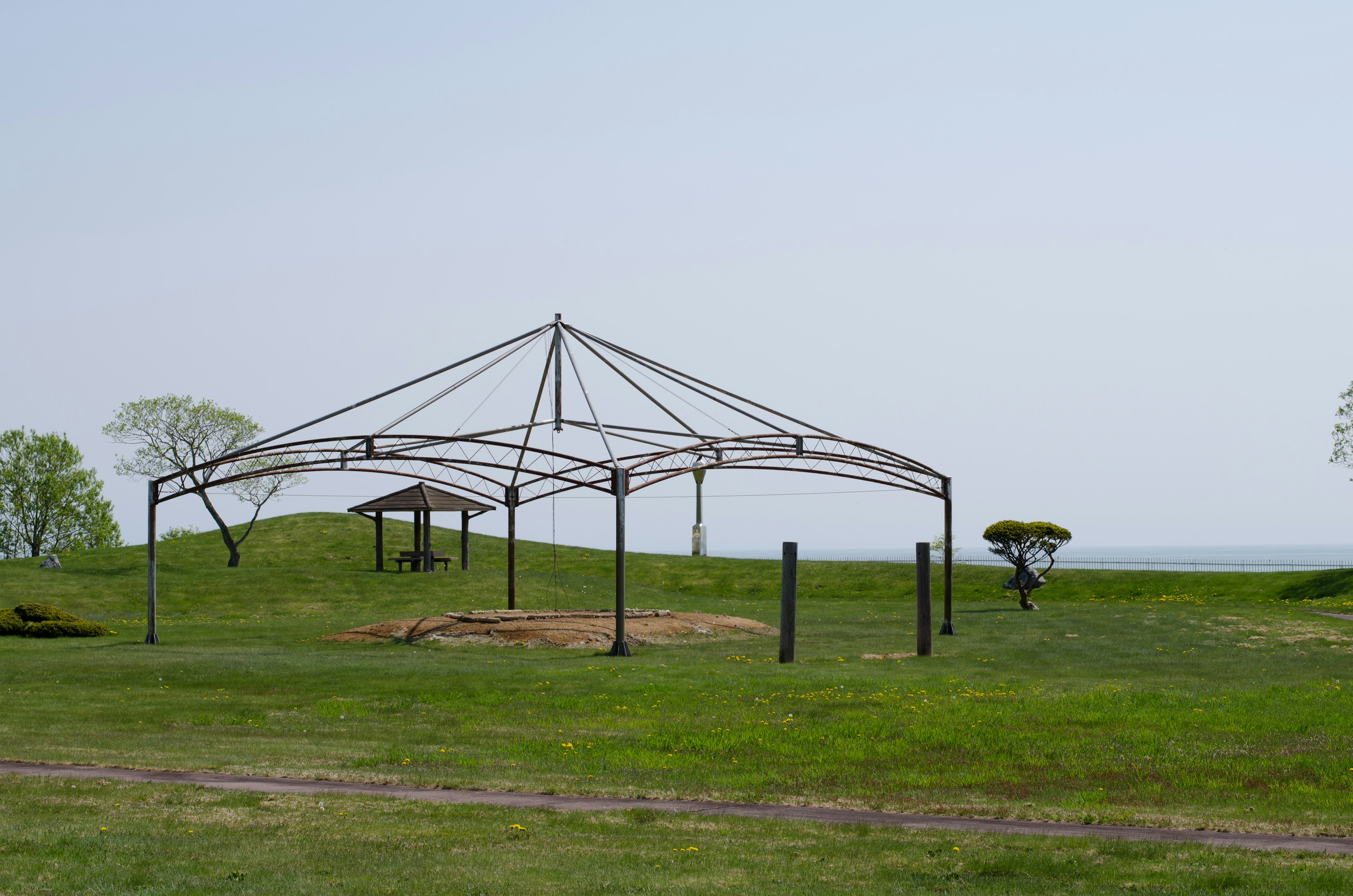 Une structure de tente en métal installée sur un champ de gazon sous un ciel ouvert