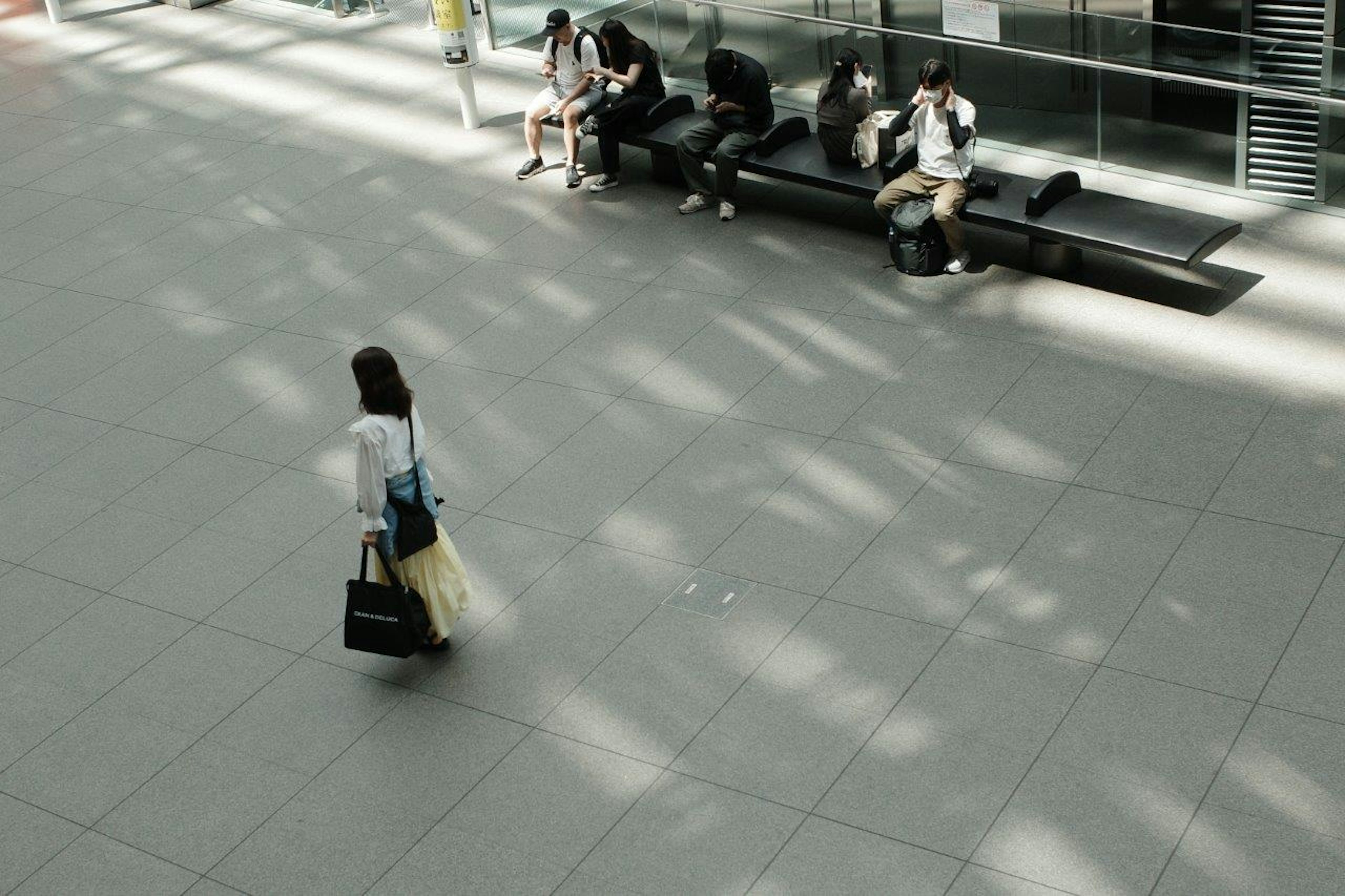 Una mujer caminando con una bolsa en el vestíbulo de un aeropuerto