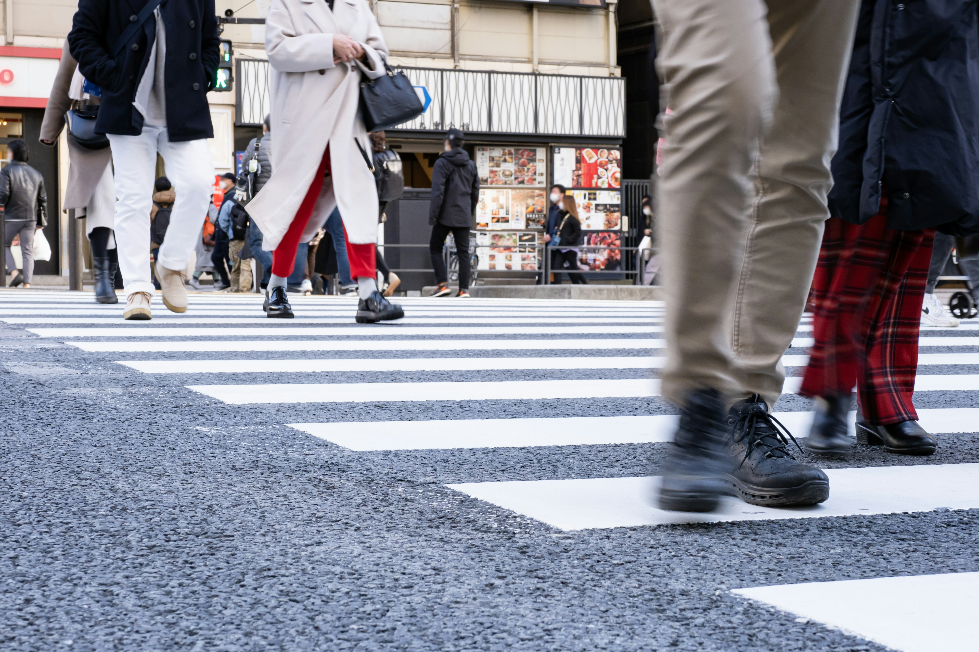 People crossing a pedestrian crosswalk with diverse shoe and pant designs