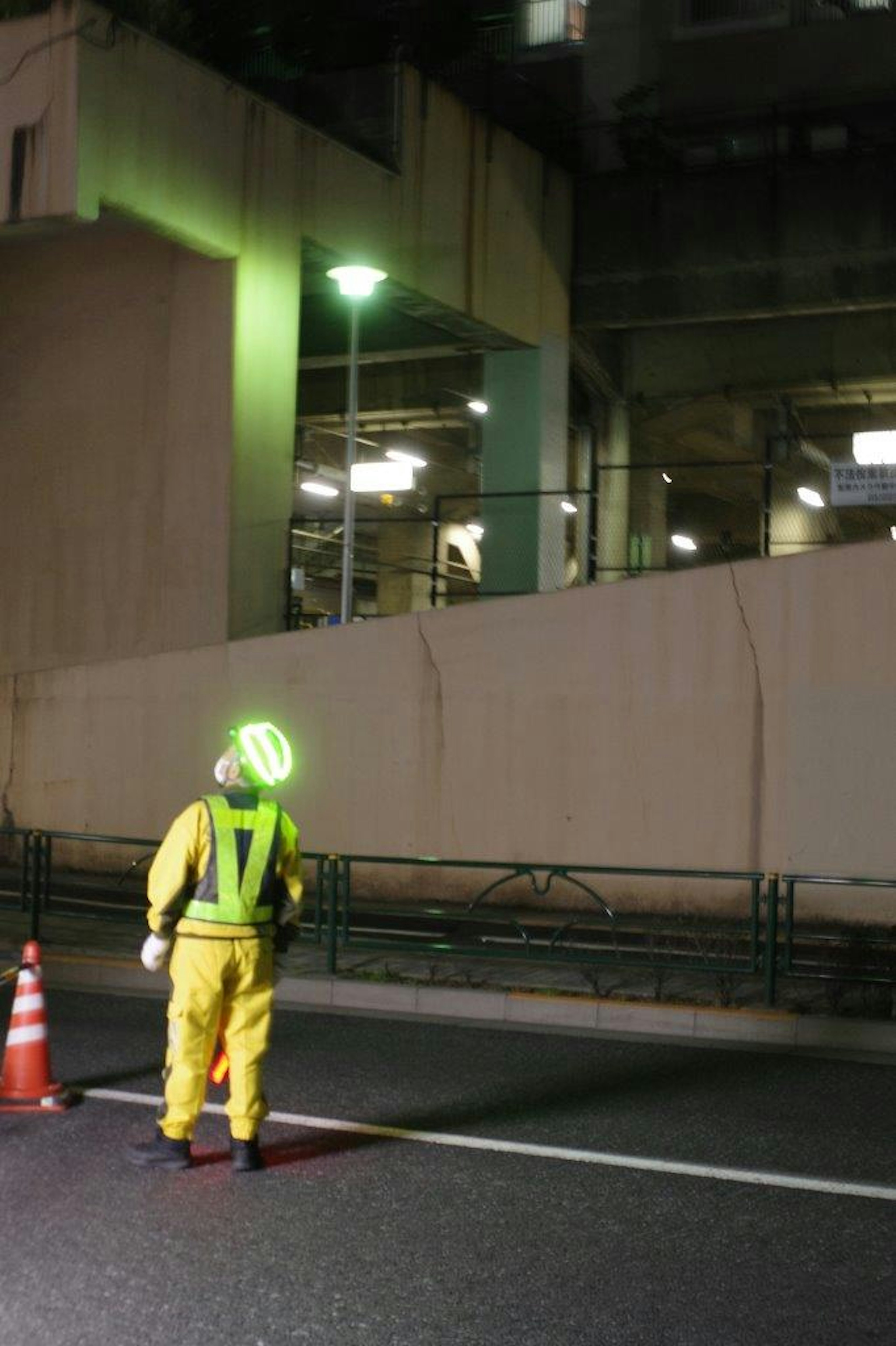 Nighttime worker wearing a green helmet monitoring the road