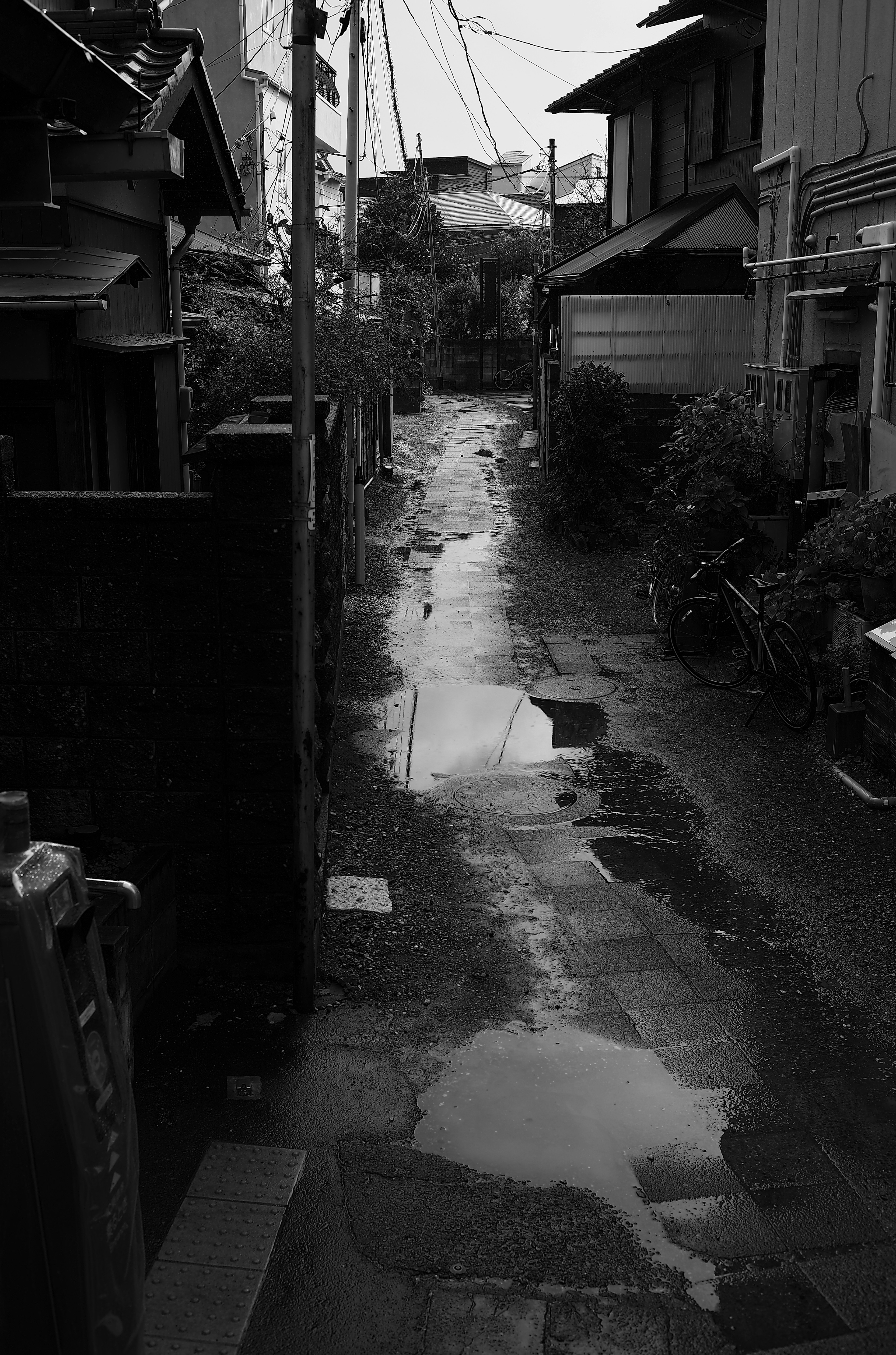 Black and white photo of a narrow alley with puddles