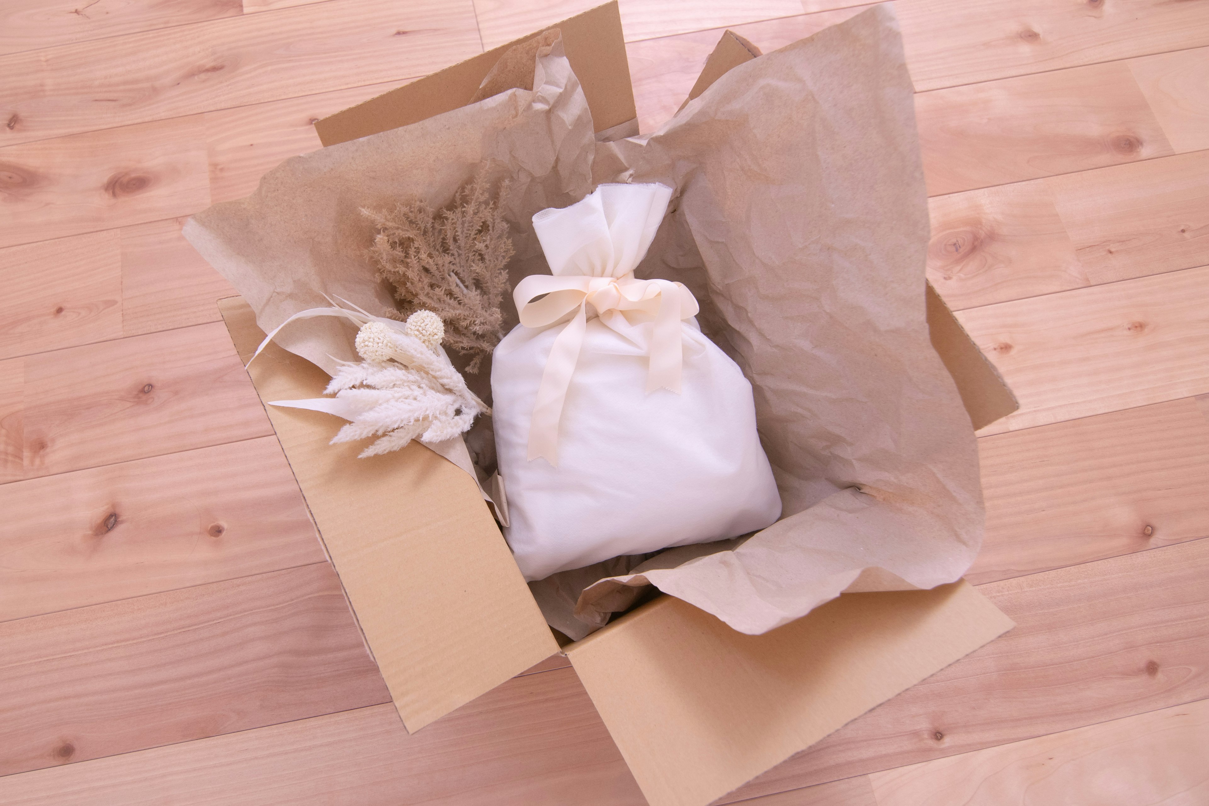 Top view of a cardboard box containing a white fabric-wrapped item and crumpled paper