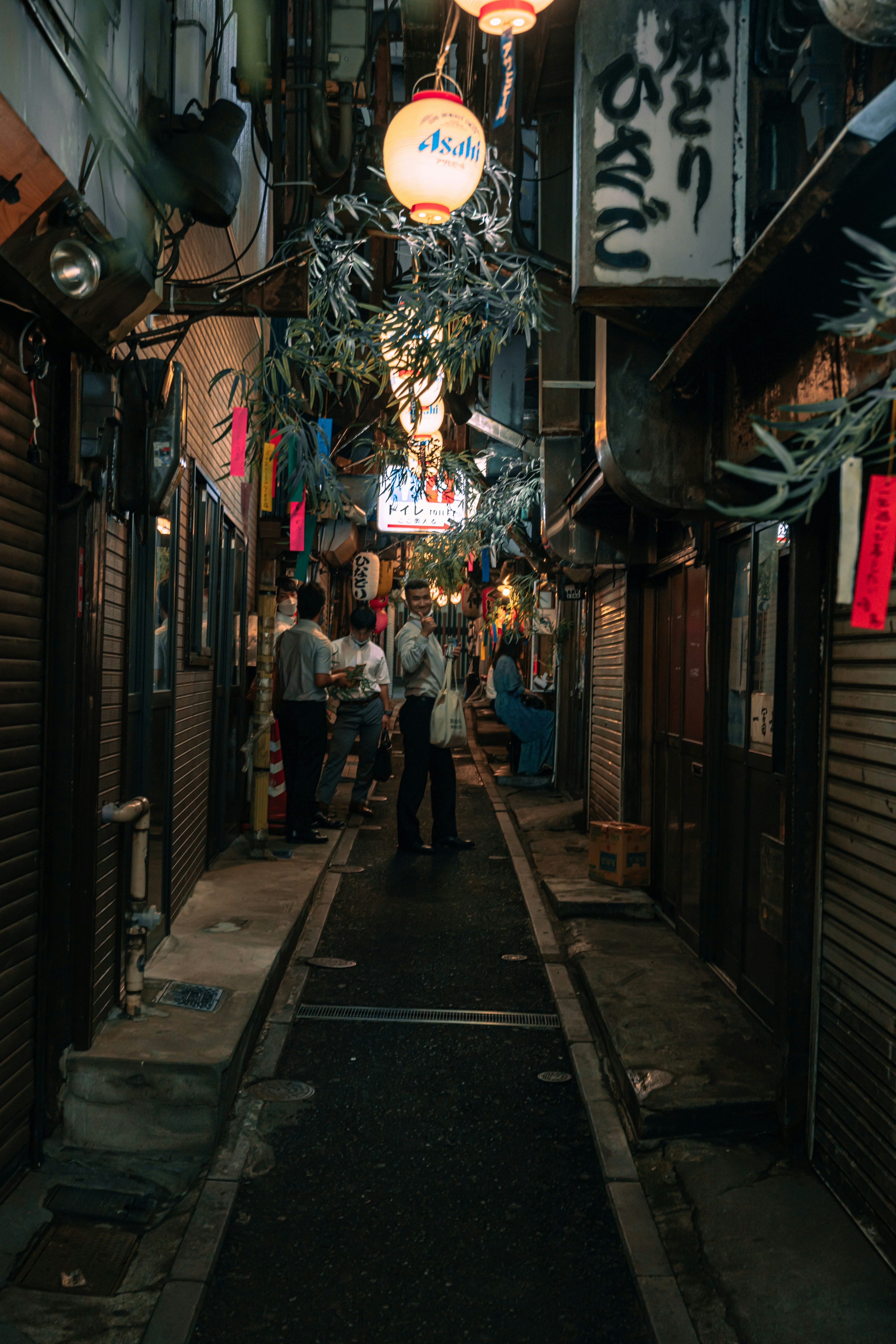 狭い路地に提灯がぶら下がり人々が集まる夜の風景