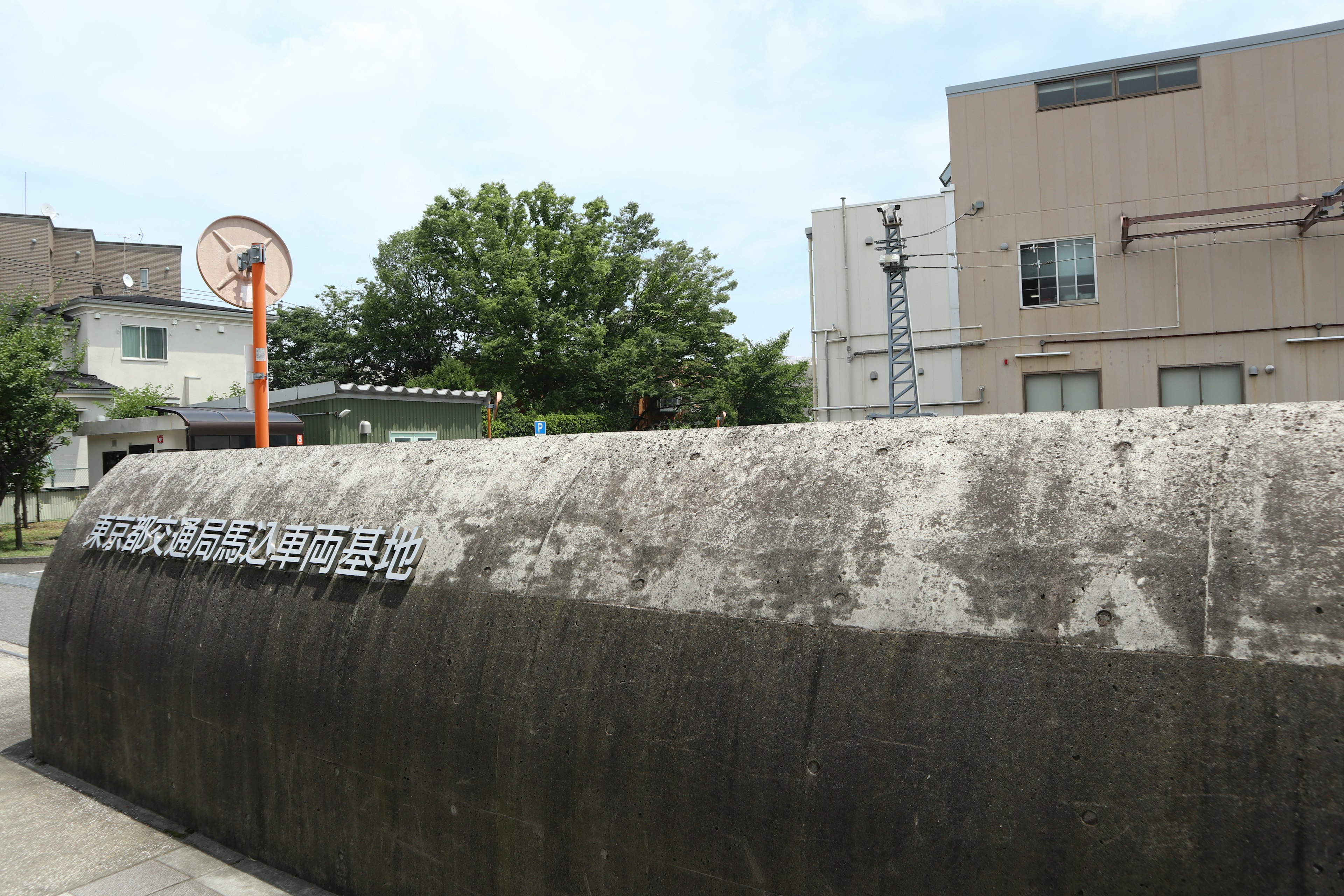 コンクリートの壁に囲まれた公園の入口とバスケットボールリング