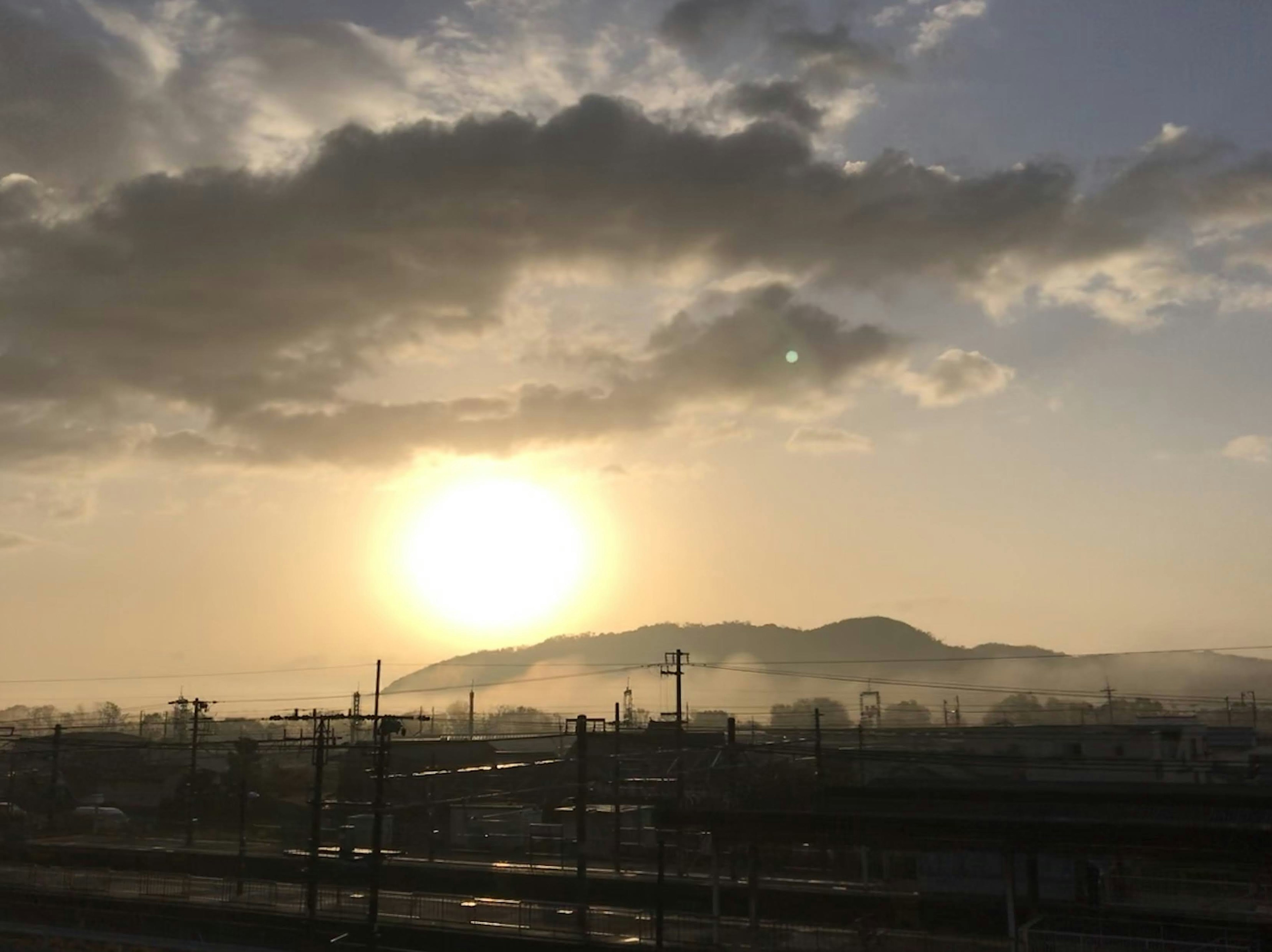 美しい夕日が雲の間から見える風景 山と鉄道が背景にある