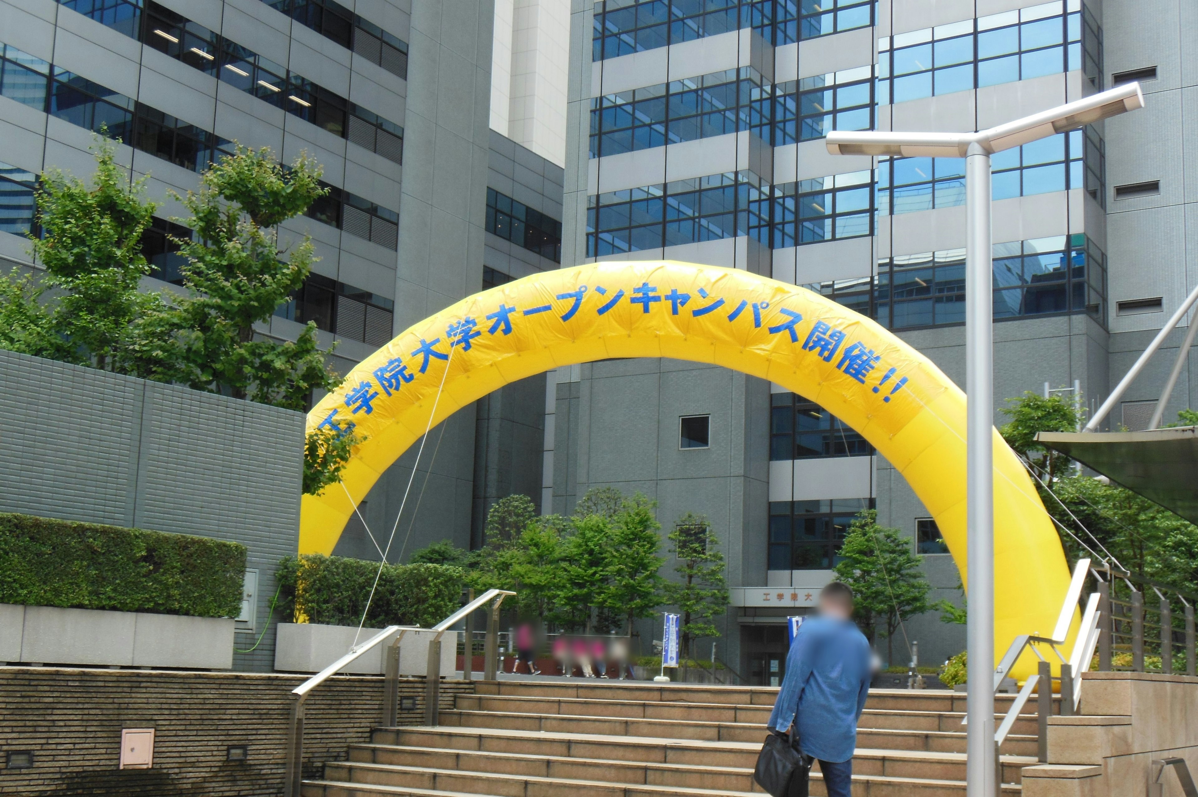 Entrée du campus universitaire avec une arche jaune et des bâtiments modernes