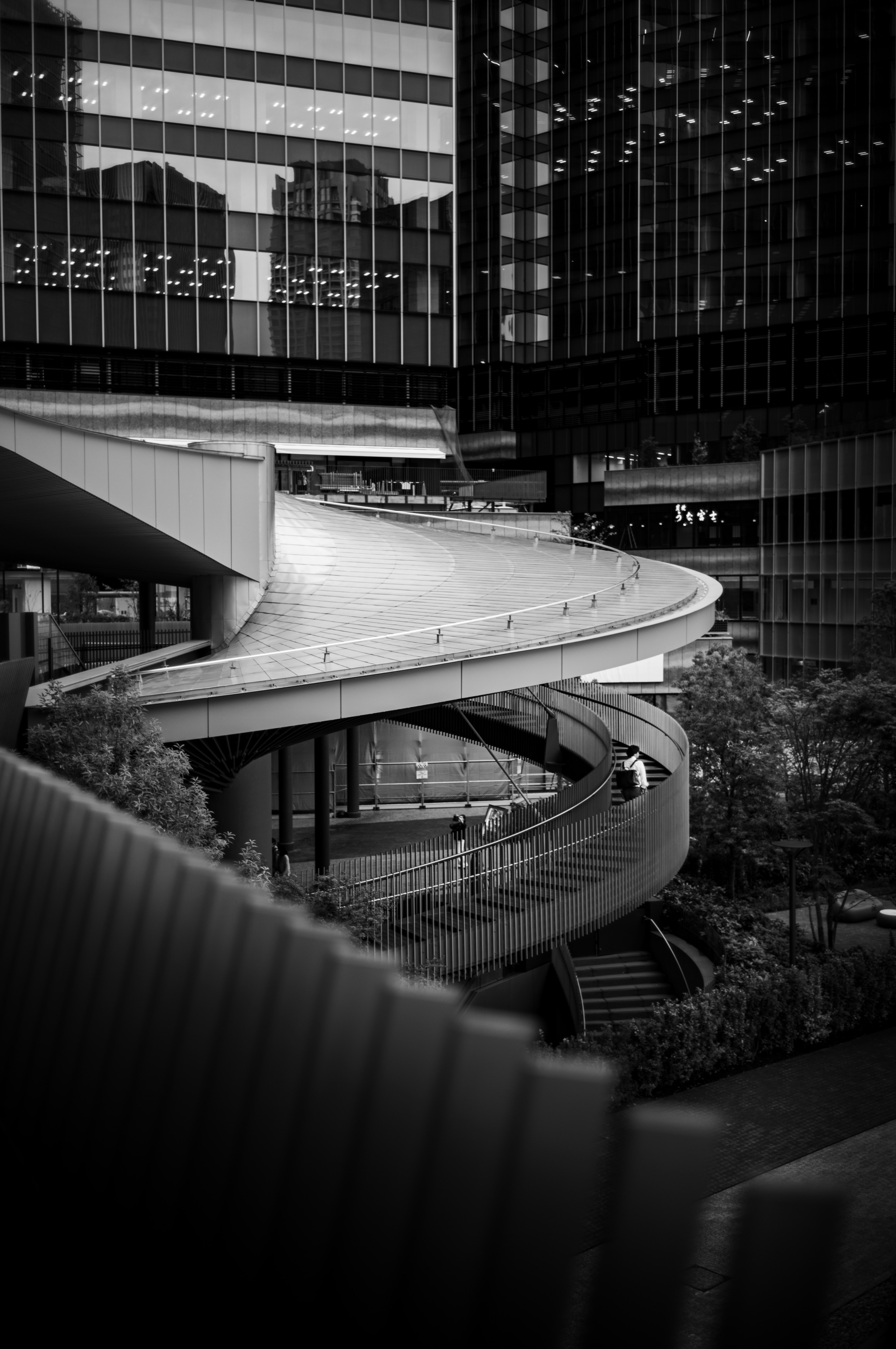 Struktur jembatan pejalan kaki melengkung dan tangga antara gedung