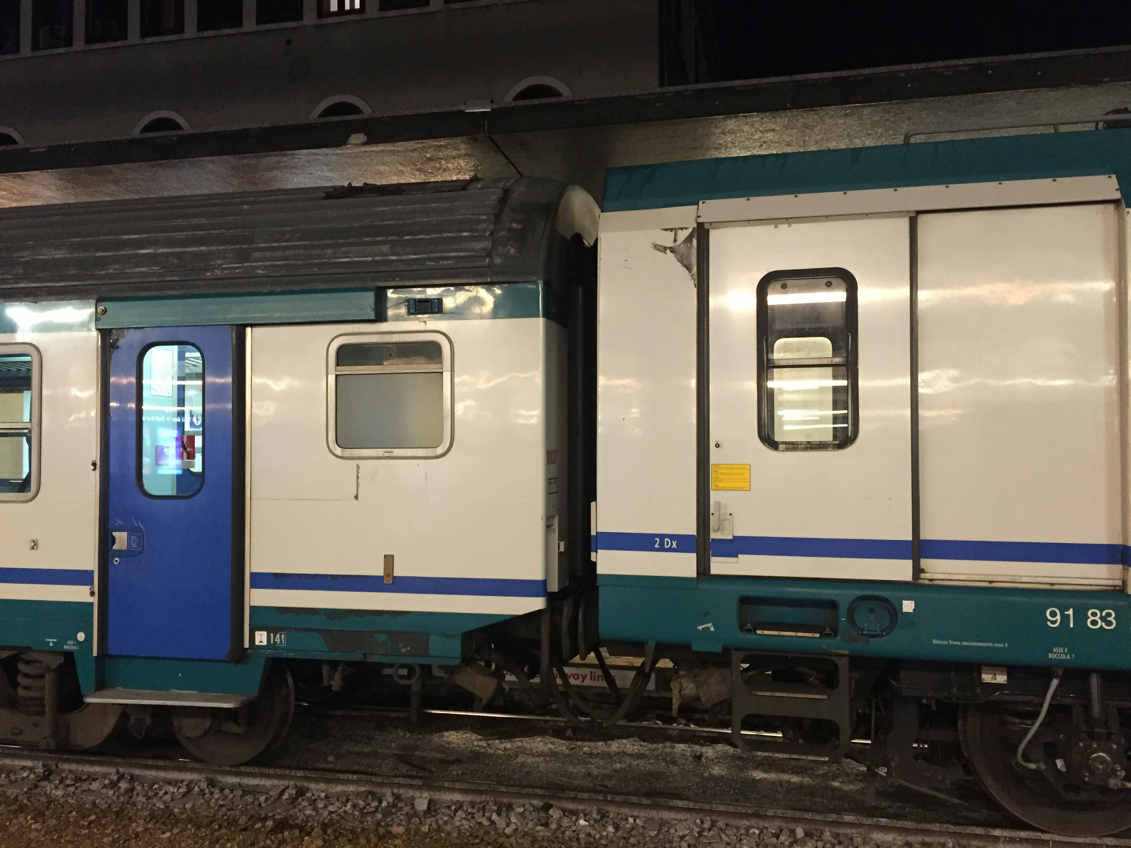 Blue and white train cars at a station during the night