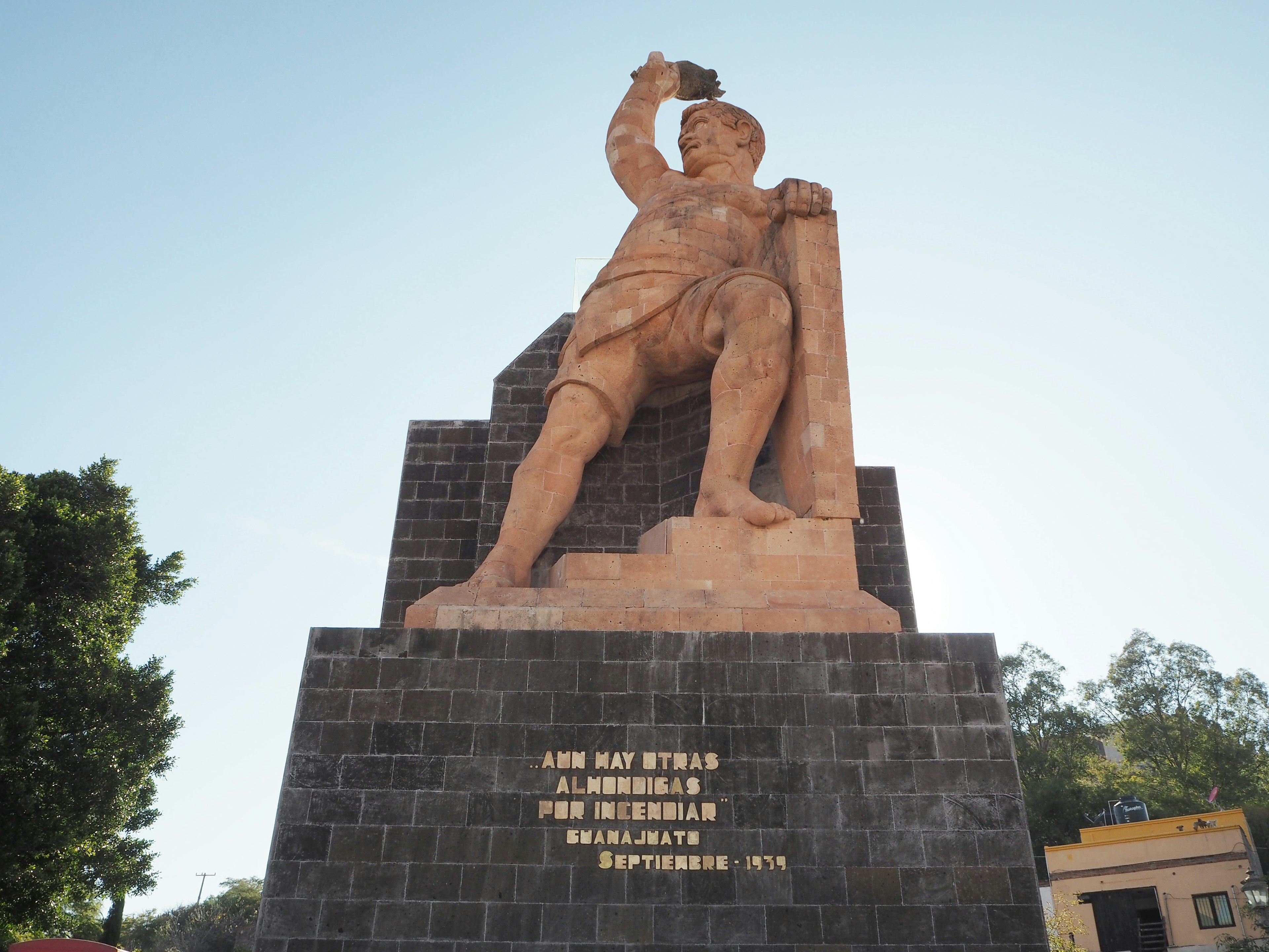 Grande statua di pietra in un parco che tiene un libro in alto