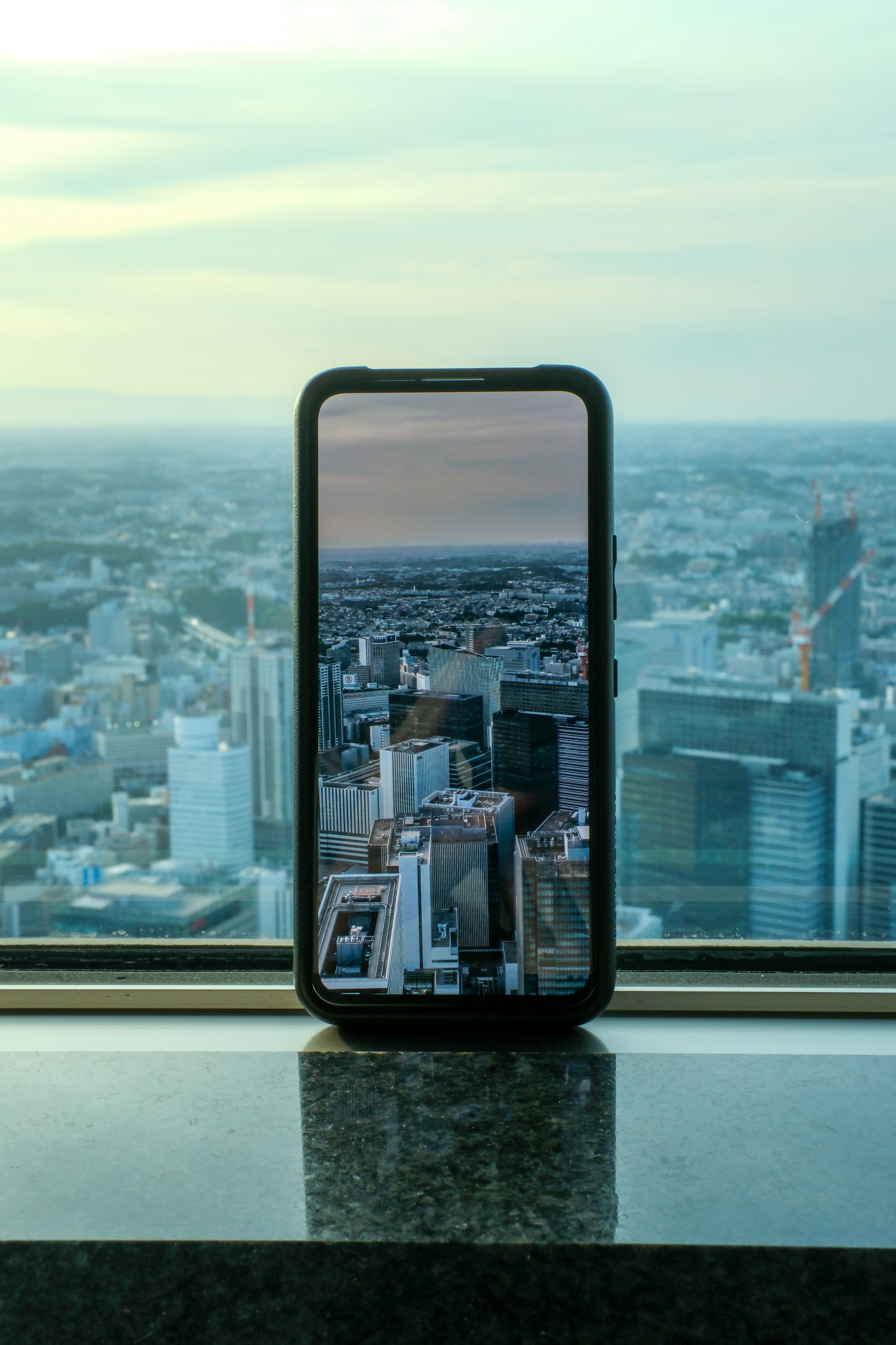 Uno smartphone che mostra un panorama urbano è posizionato vicino alla finestra