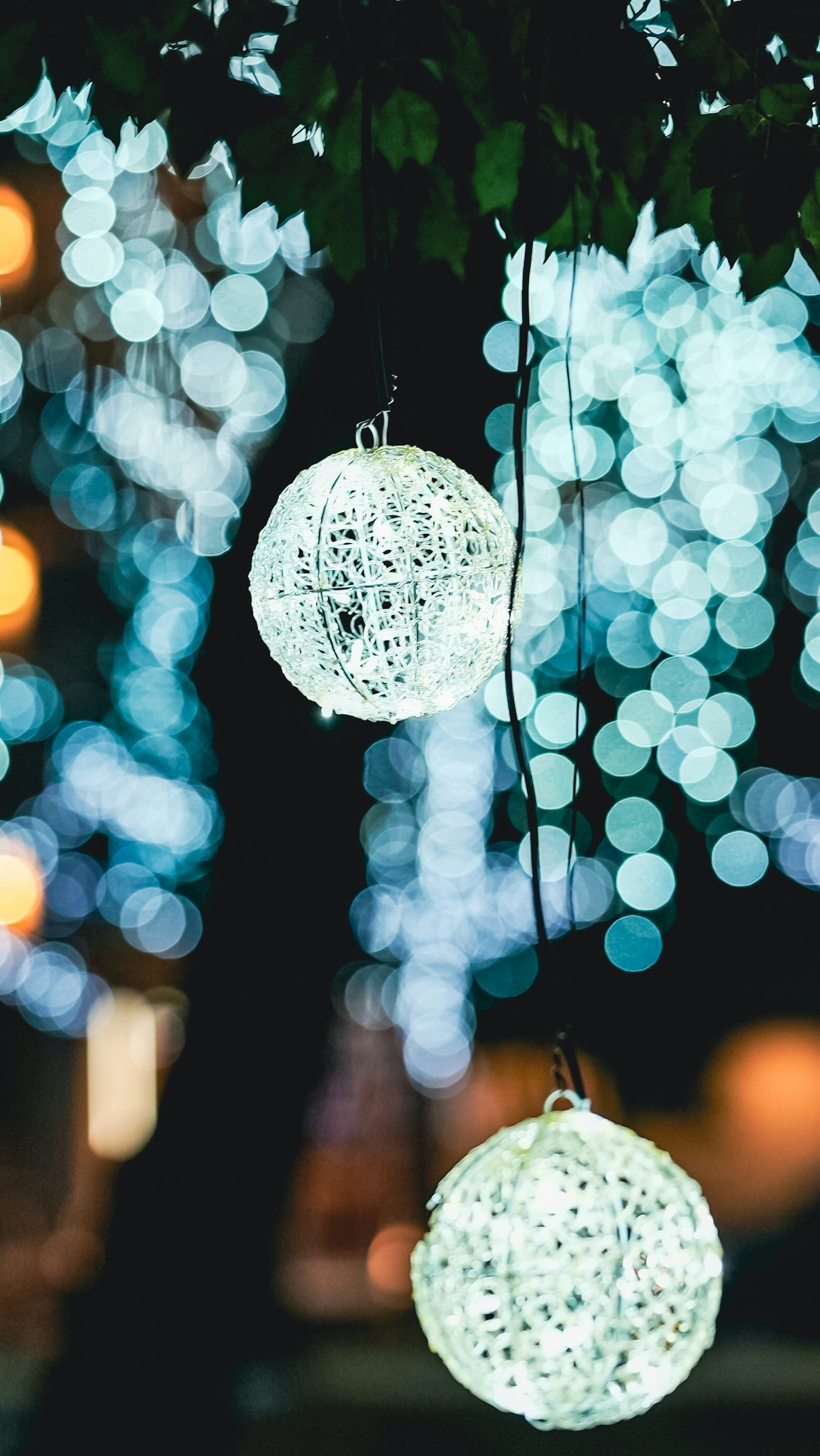 Weiße Laternen hängen vor einem blauen Bokeh-Hintergrund in der Nacht