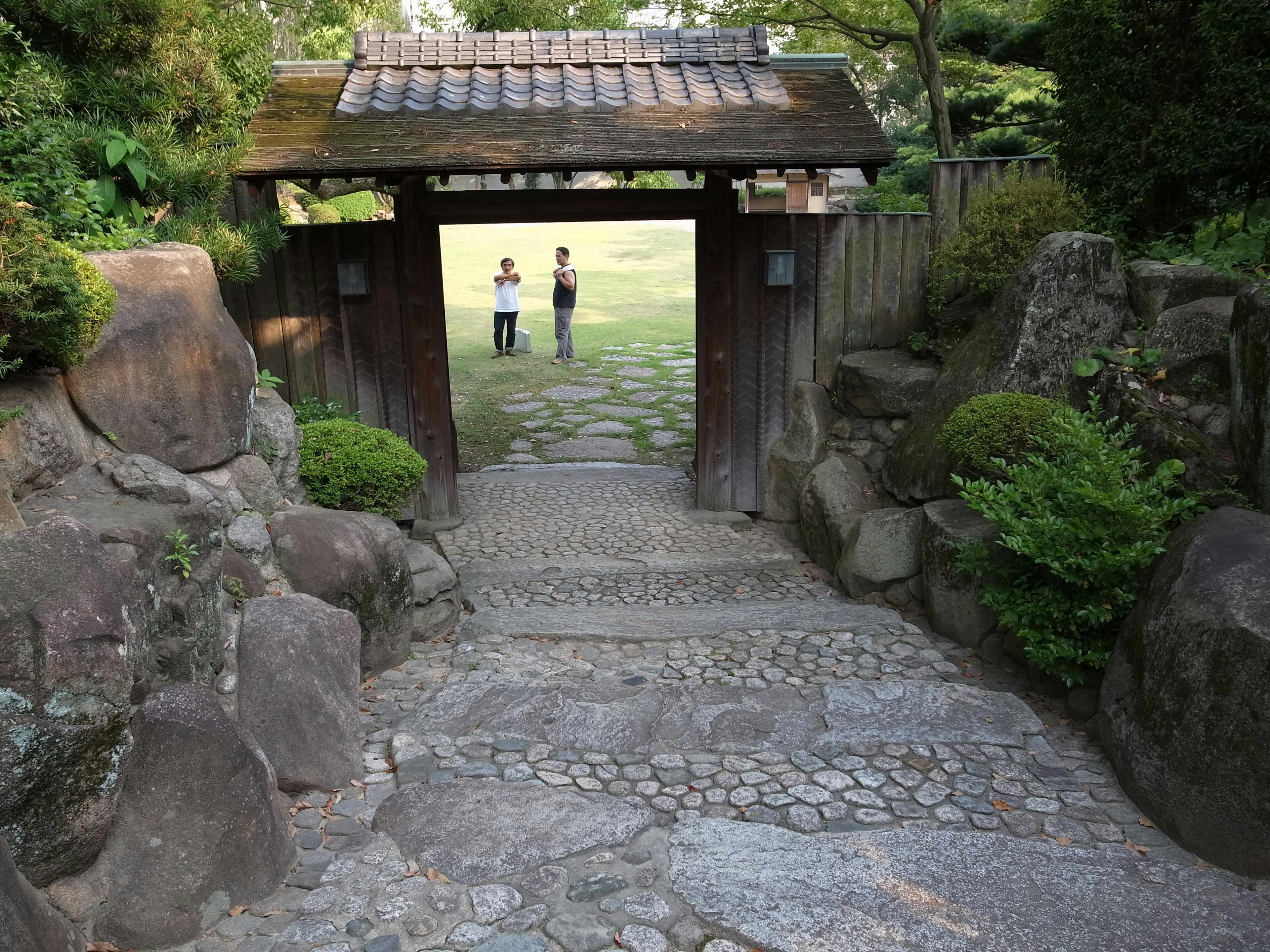 Entrée d'un jardin japonais avec des marches en pierre et une porte en bois