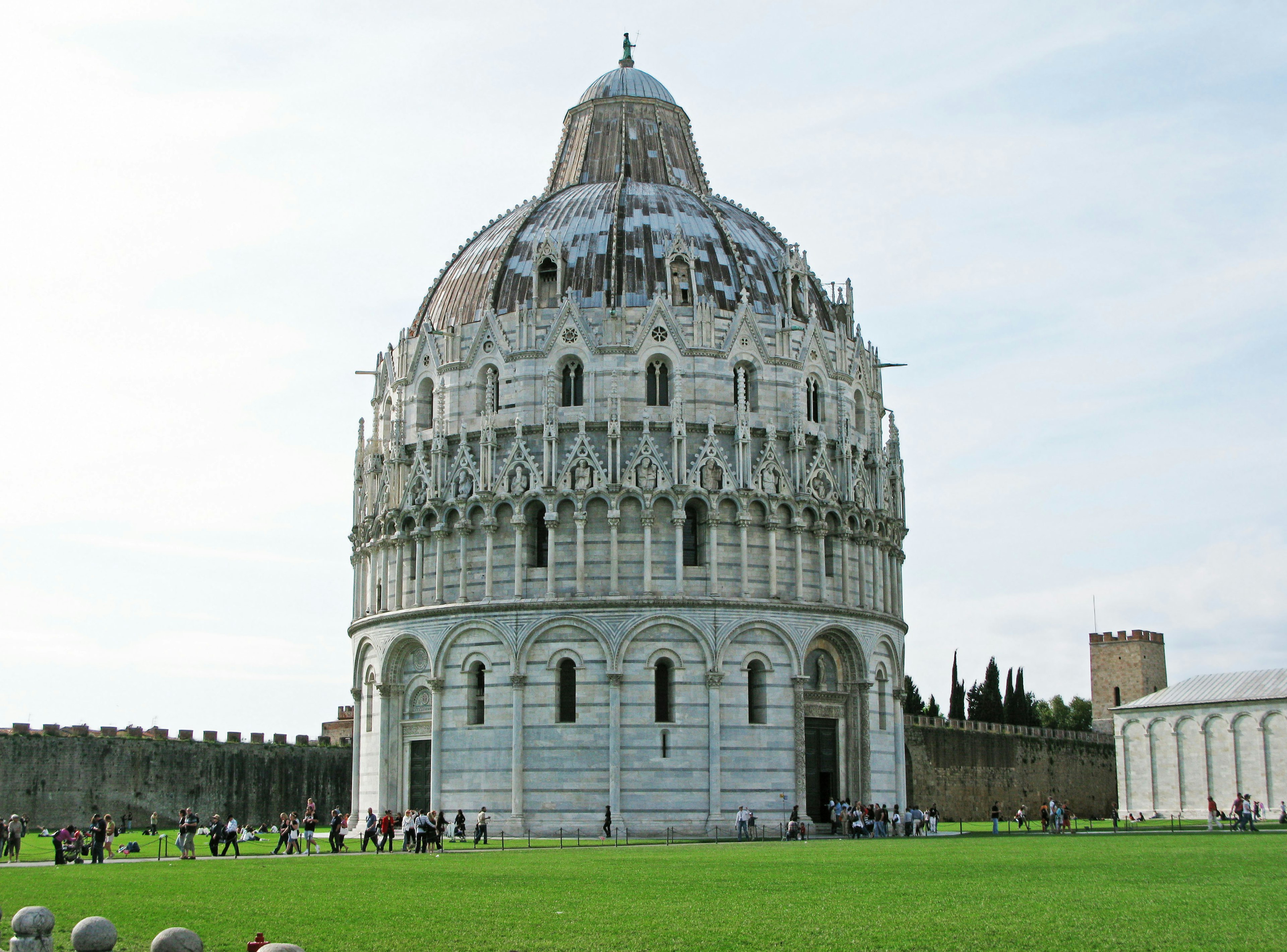 El exterior impresionante del Baptisterio de Pisa con césped verde