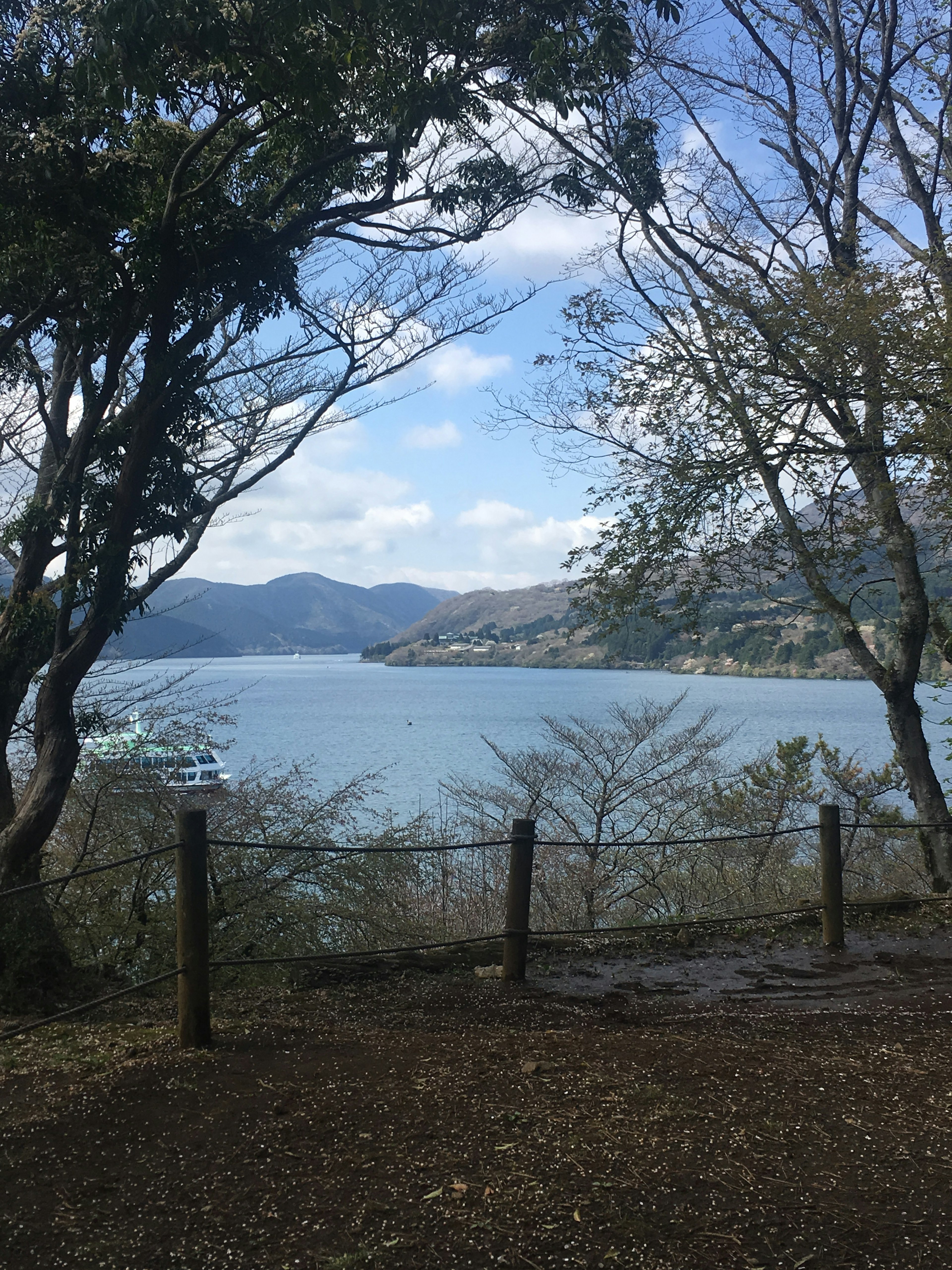 Malersicher Blick auf einen ruhigen See, umgeben von Bergen und Bäumen unter einem blauen Himmel