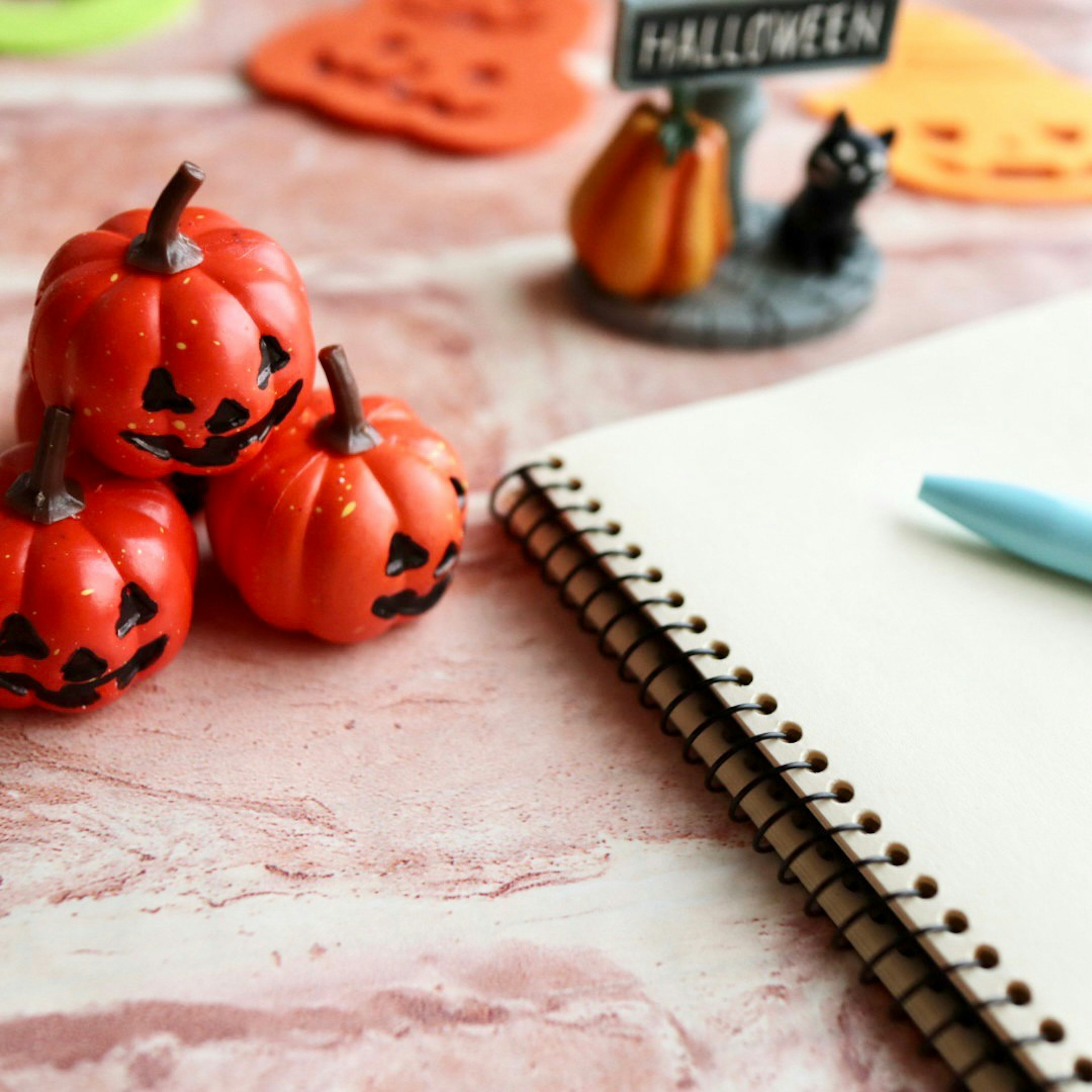 Kecil labu oranye Halloween dan buku catatan kosong di atas meja