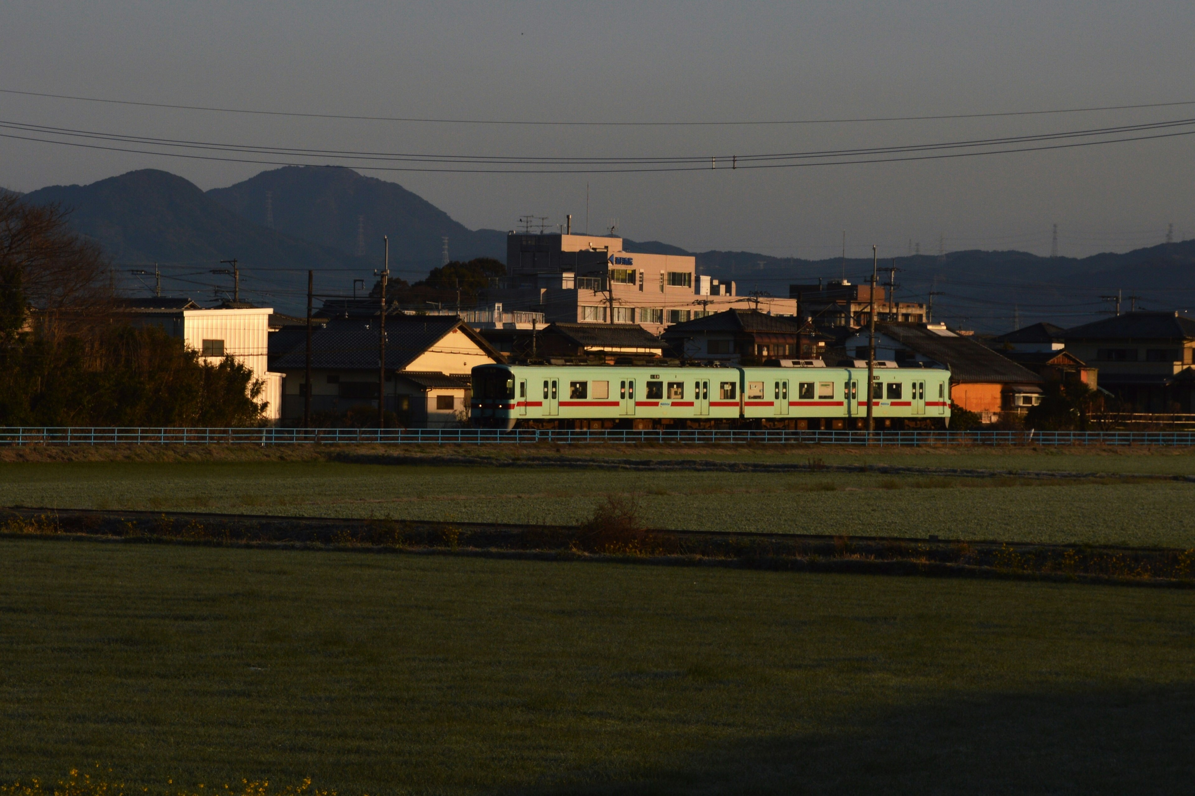 Un tren azul con montañas hermosas y casas de campo tranquilas de fondo