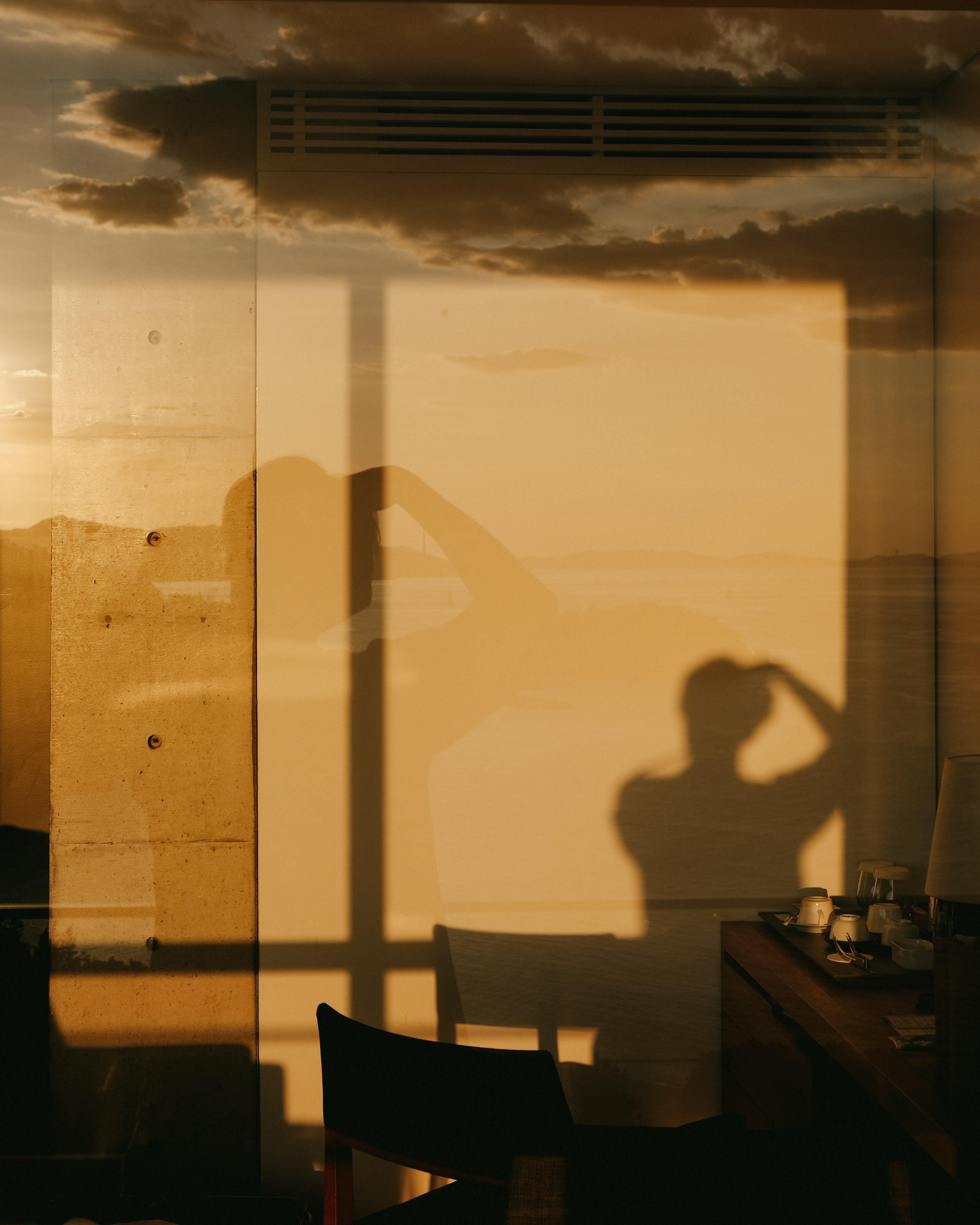 Interno con l'ombra di una persona contro uno sfondo di tramonto