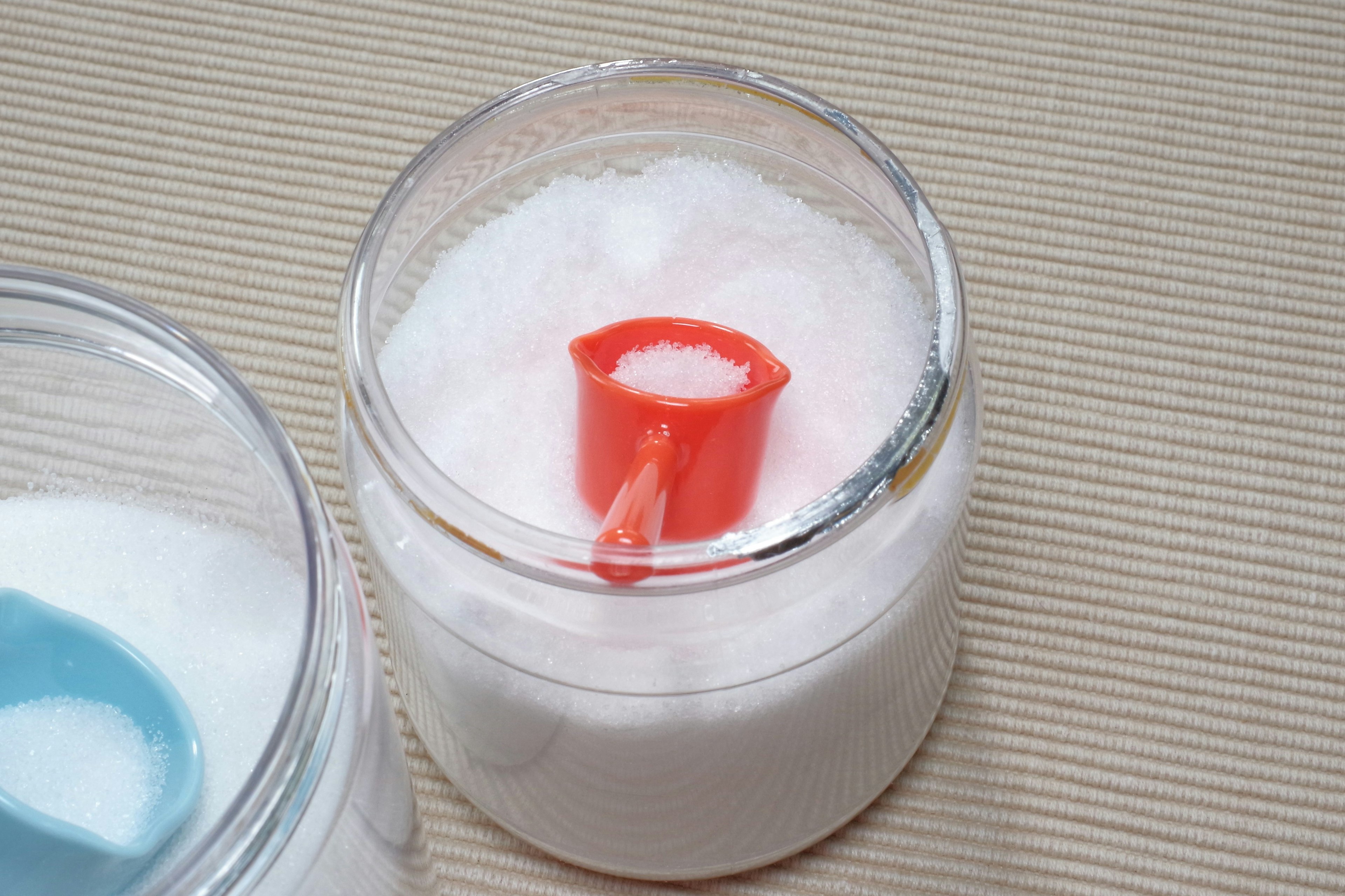 Transparent container with white powder and a red scoop