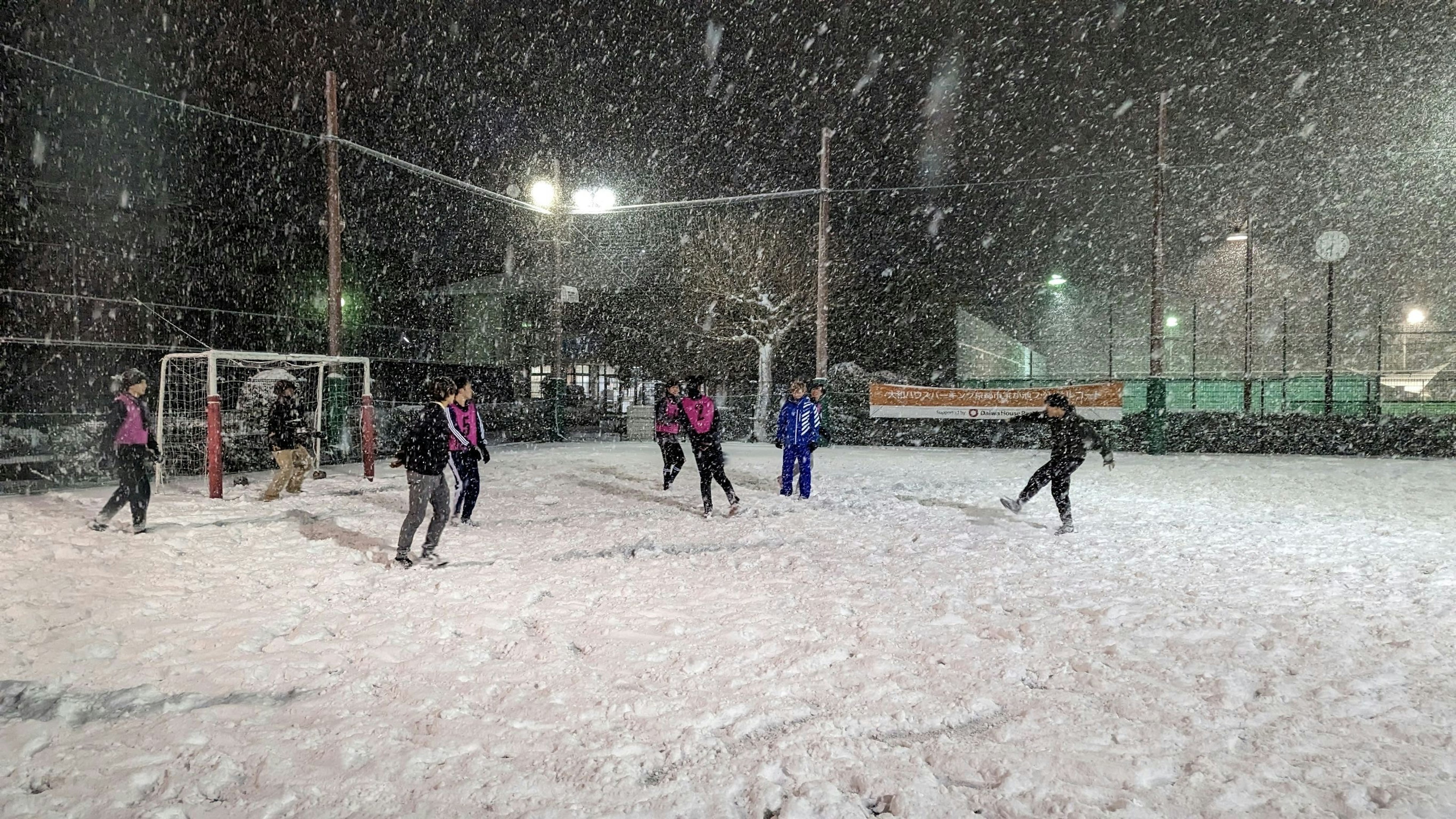 夜间在雪中踢足球的球员