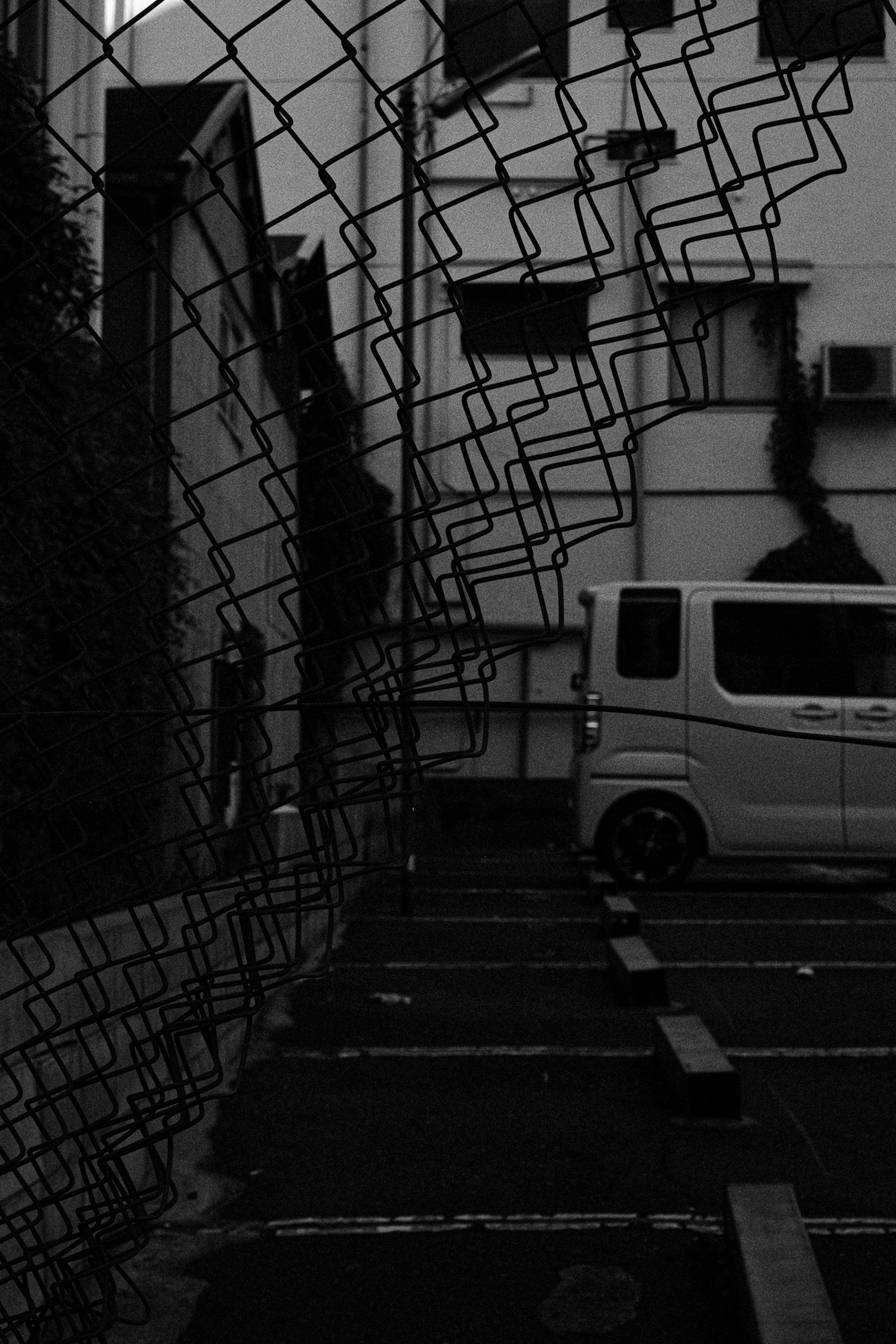 Parking en noir et blanc avec un véhicule et une clôture en filet