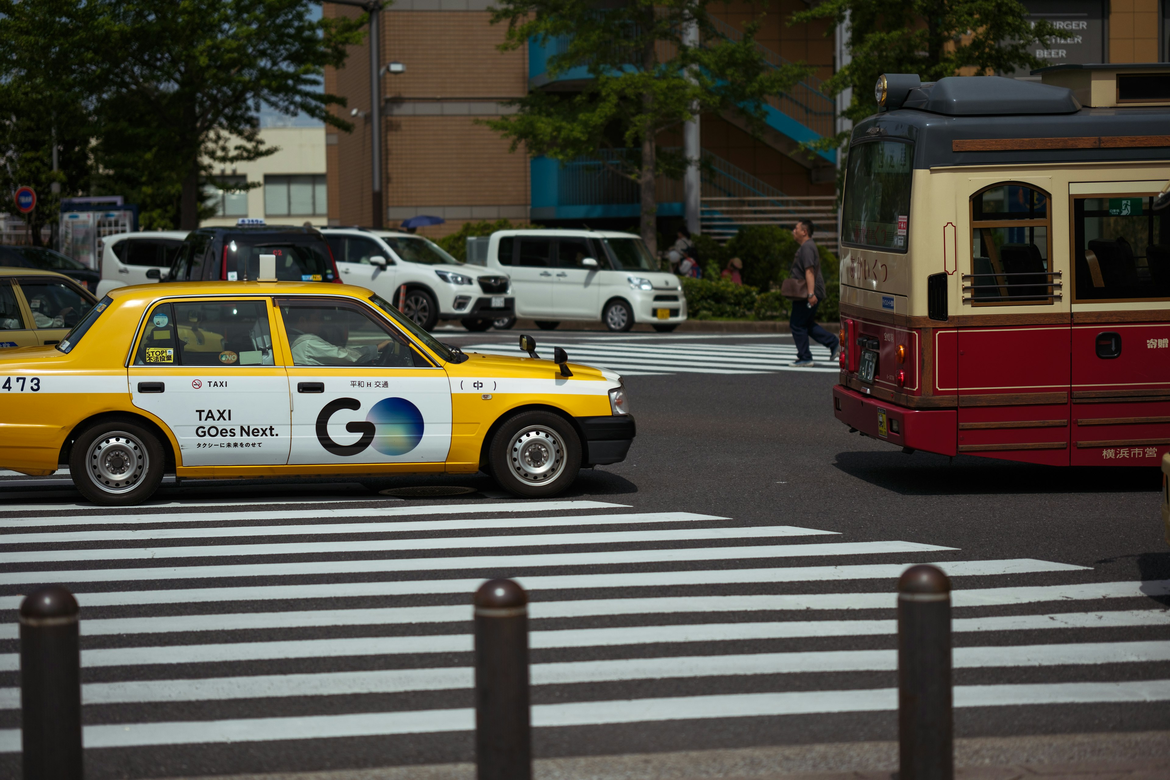 Gelber Taxi und Retro-Bus an einem Zebrastreifen in einem belebten Stadtgebiet