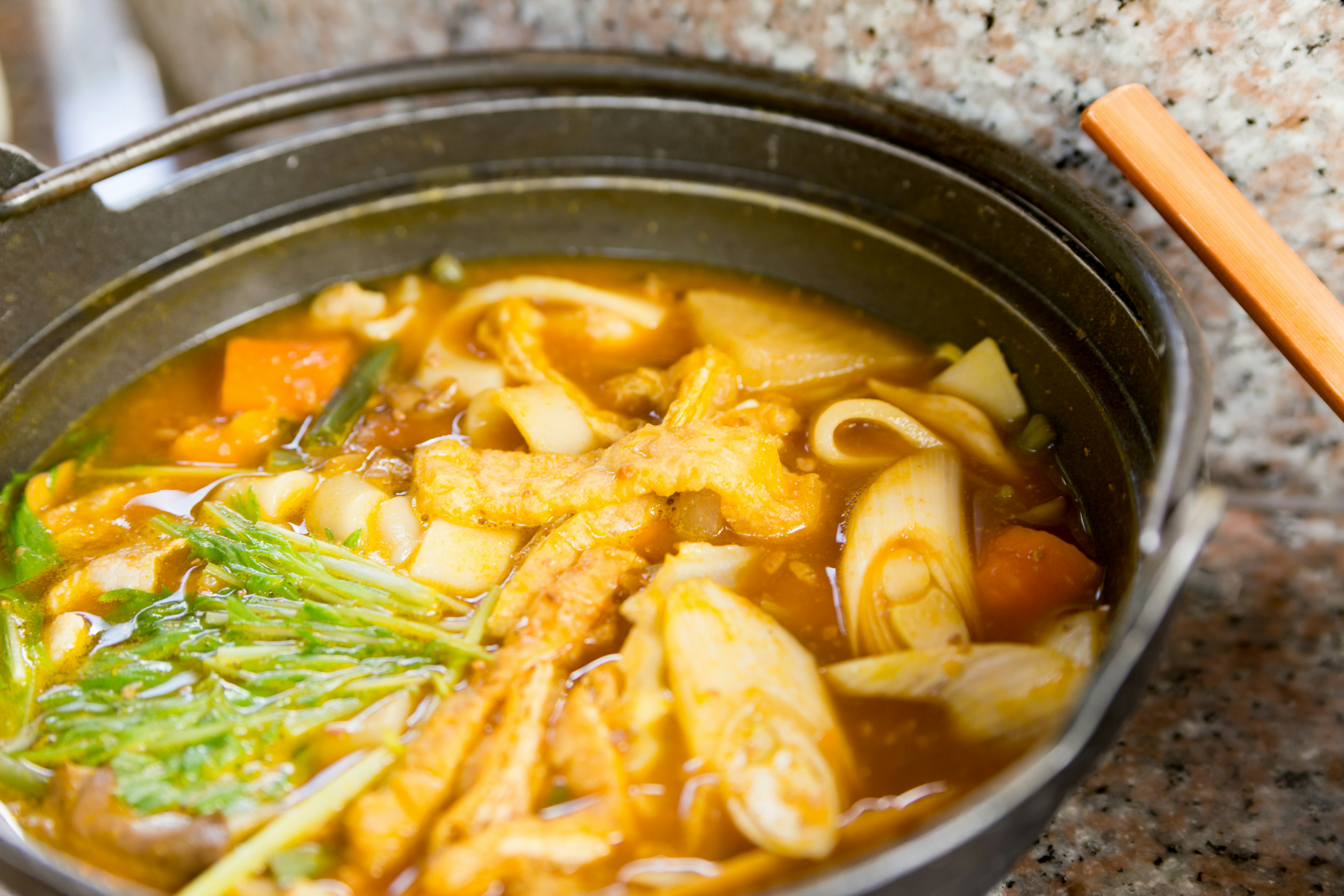 温かい鍋料理に麺と野菜が入ったスープ