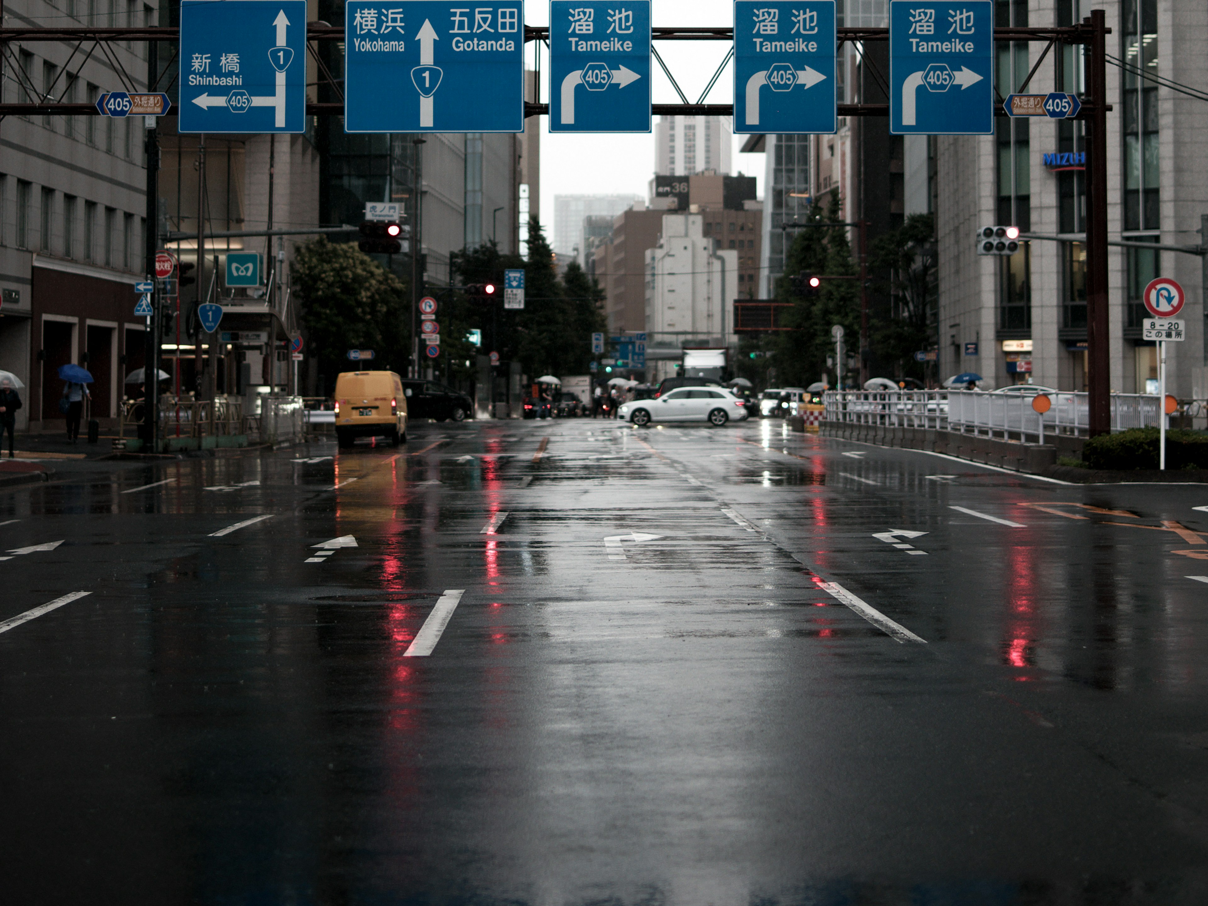 Strada bagnata con segnali stradali blu in un contesto urbano