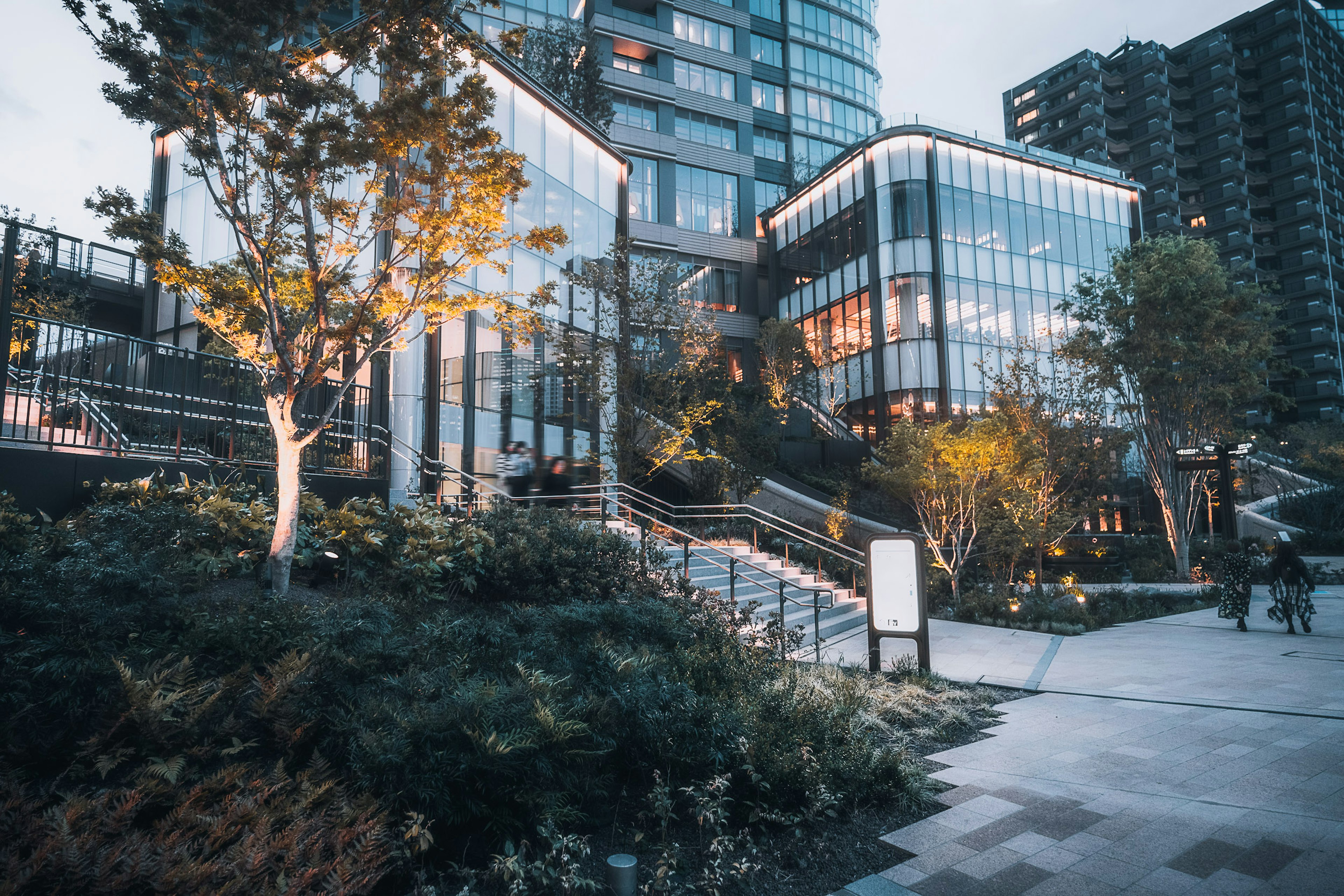 Modernes Gebäude mit Glasfassade umgeben von Grünflächen und Stadtlandschaft