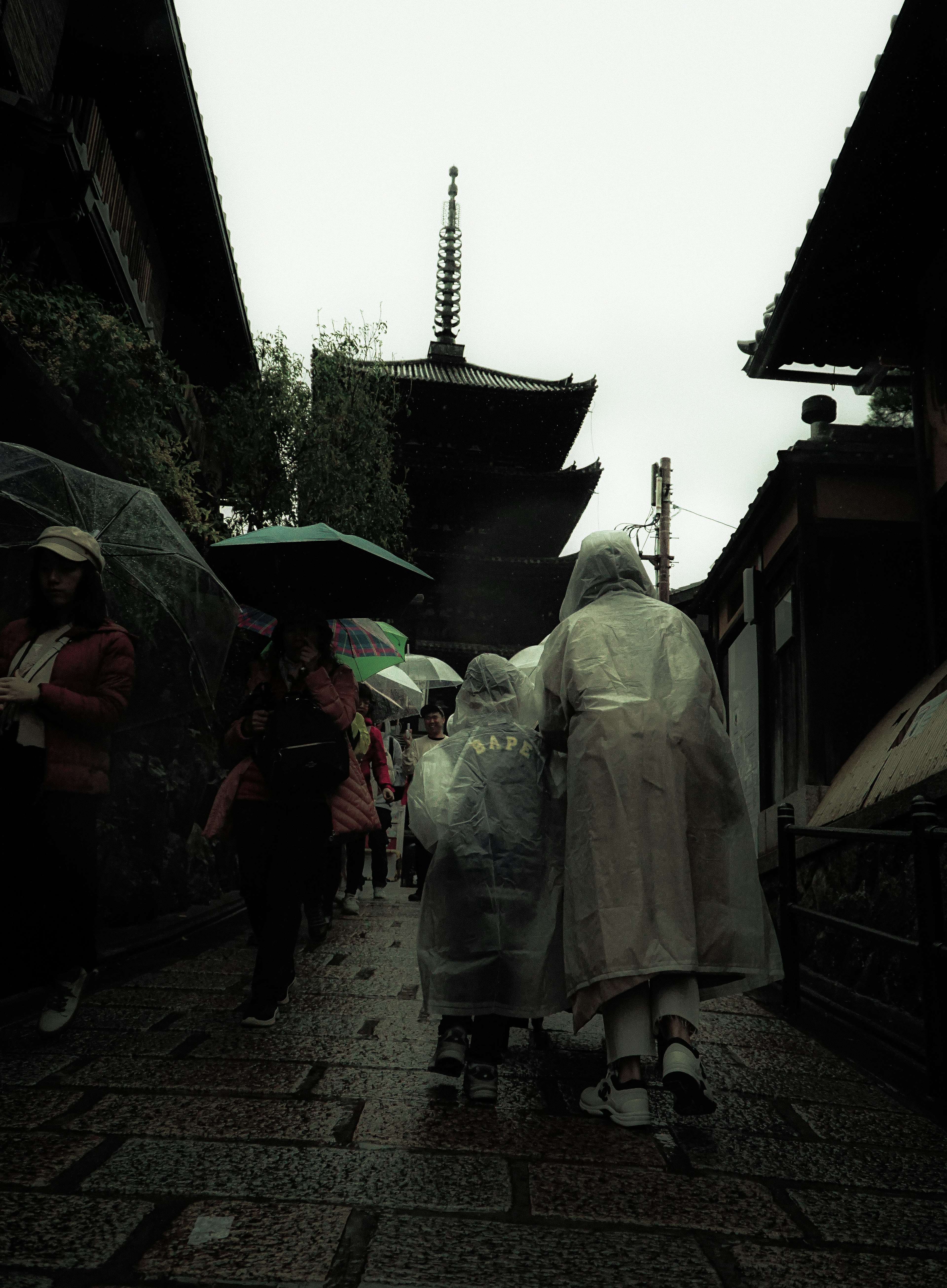 雨中撑伞行走的人们和寺庙轮廓