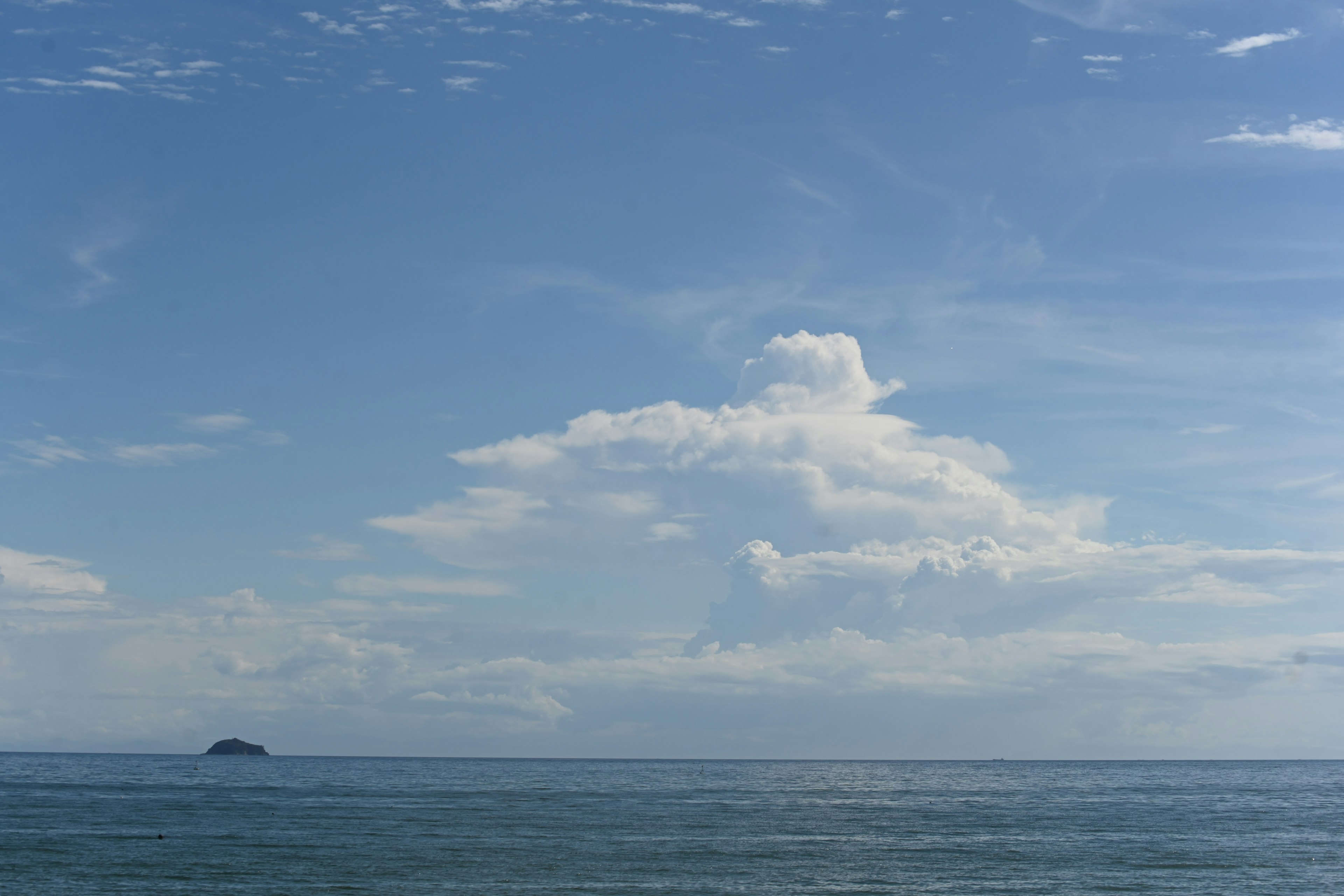 青い空と雲が広がる海の風景小さな島が遠くに見える