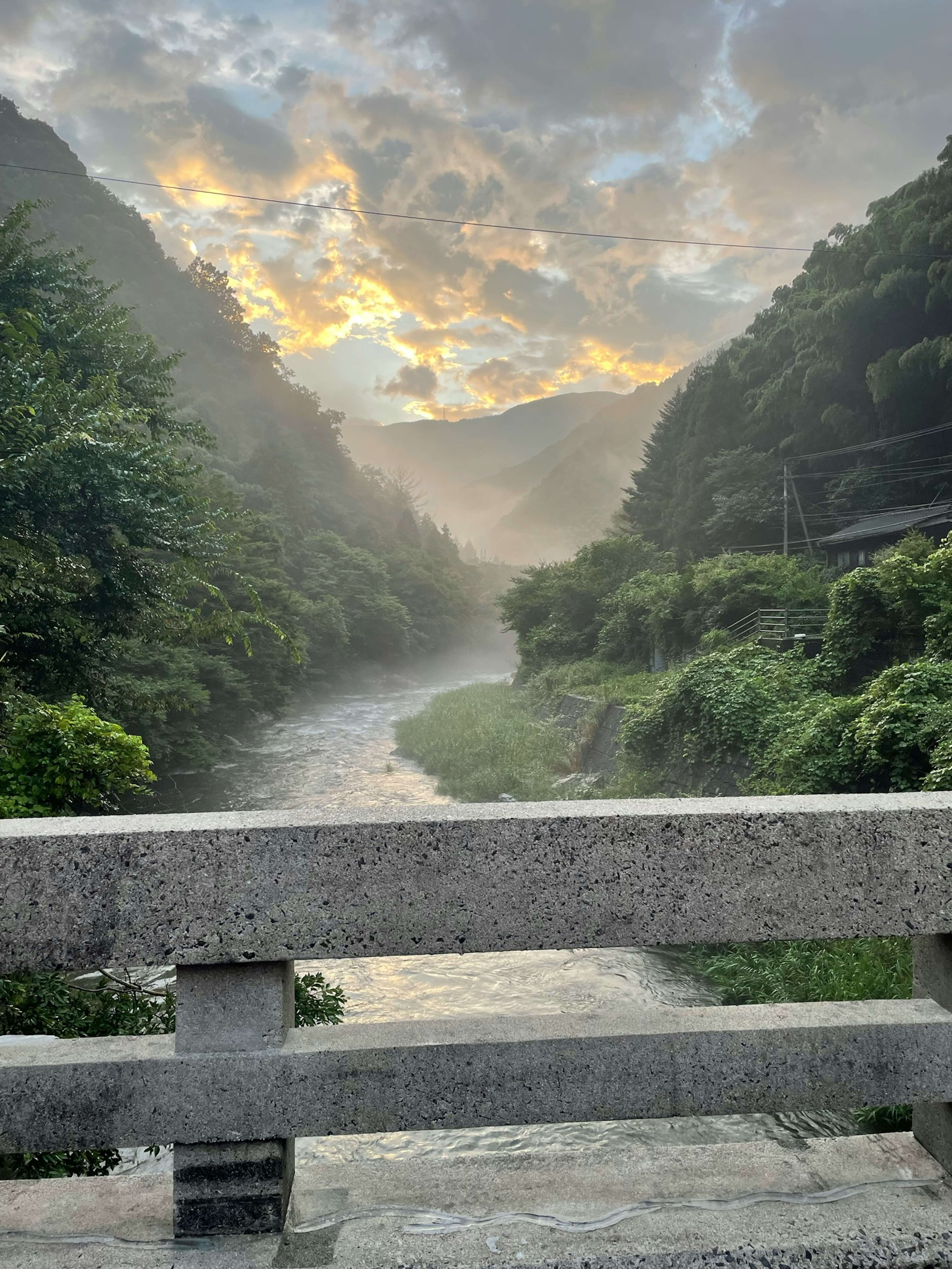 川と山々の景色に夕焼けの光が映える風景