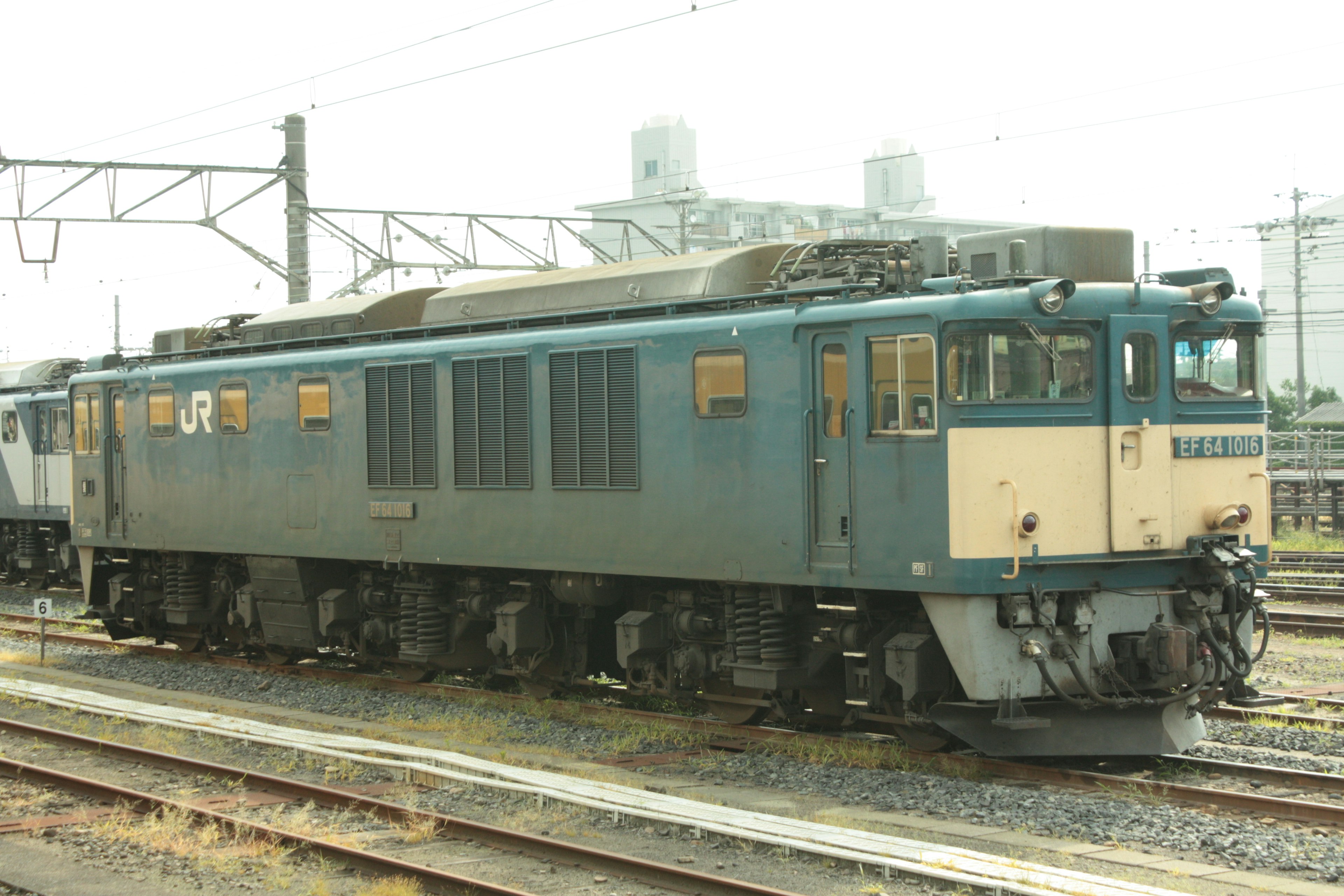 Blue electric locomotive parked beside railway tracks