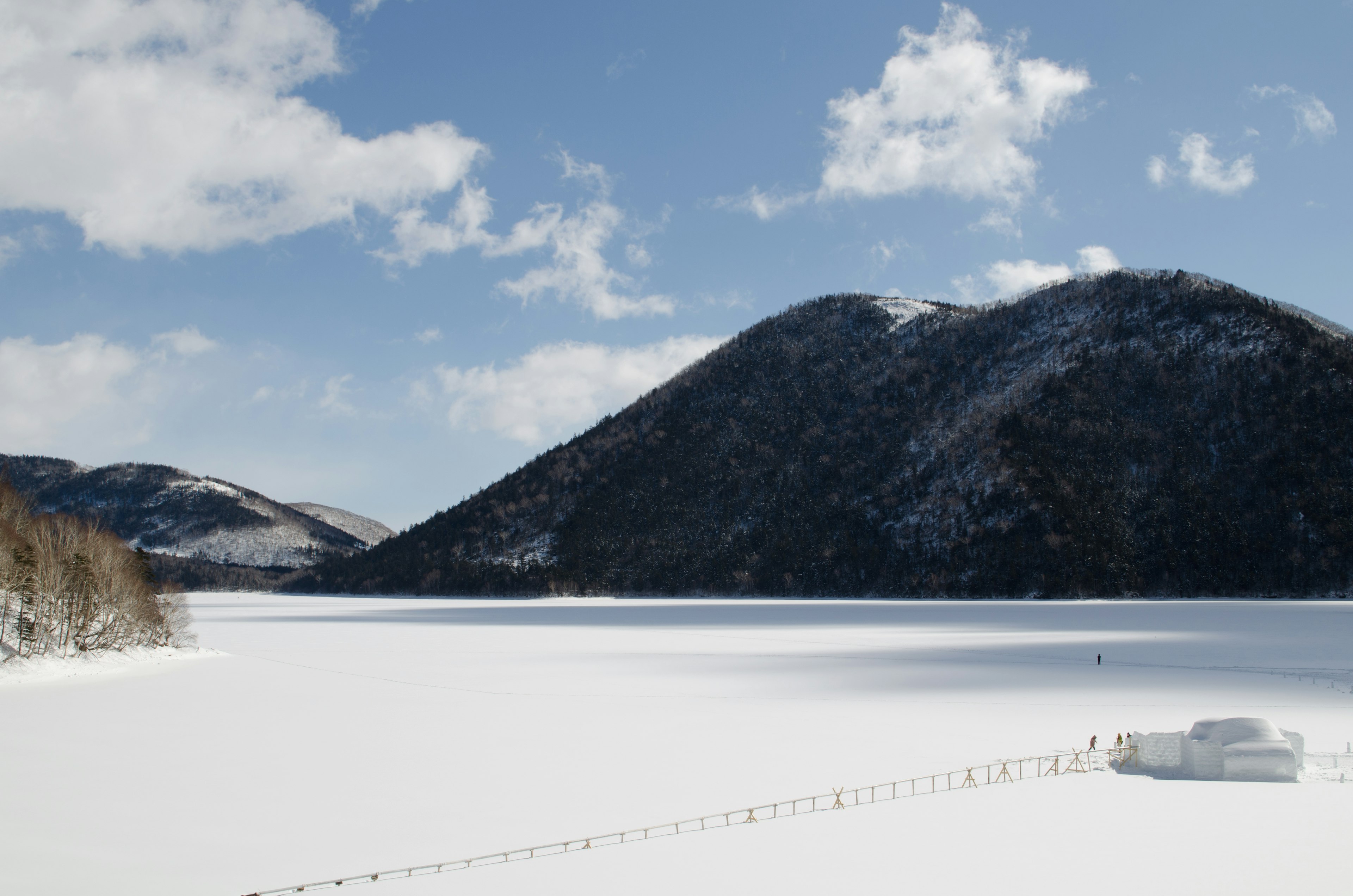 Schneebedeckte Seen- und Berglandschaft mit blauem Himmel und Wolken