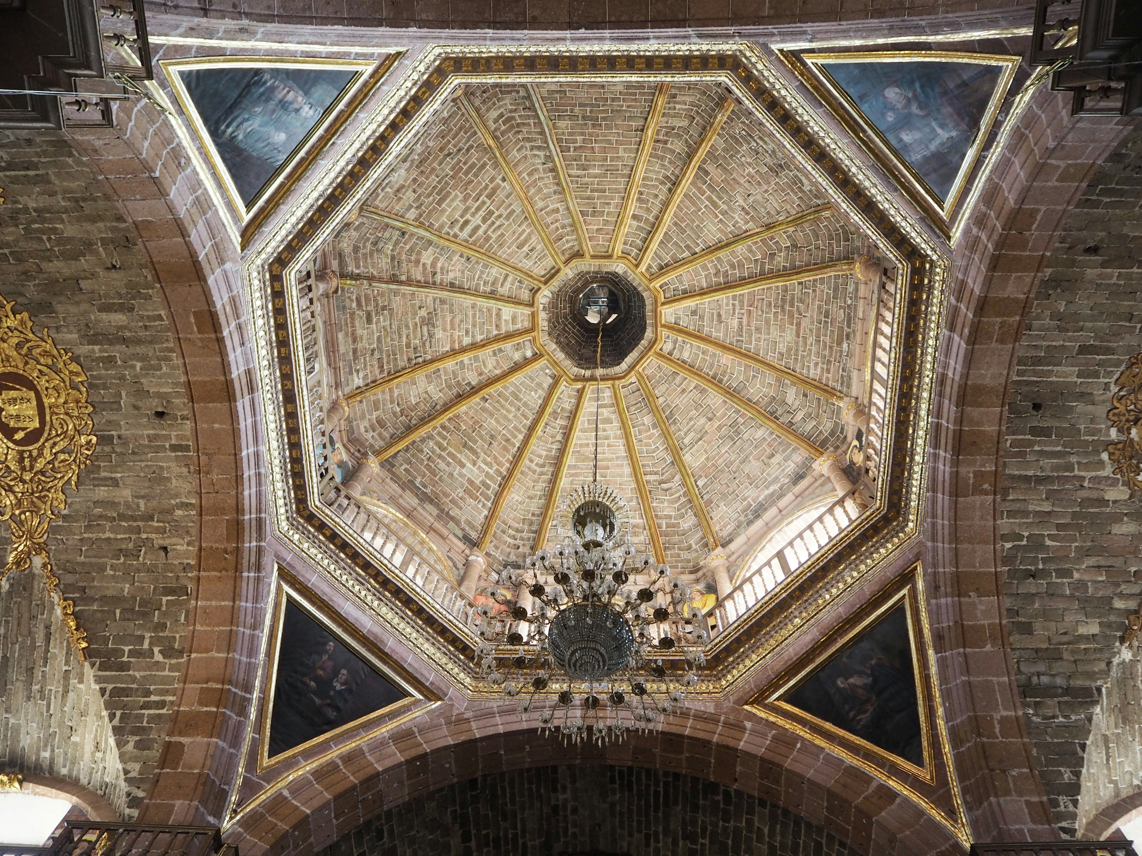 Octagonal ceiling with intricate decorations and a central chandelier