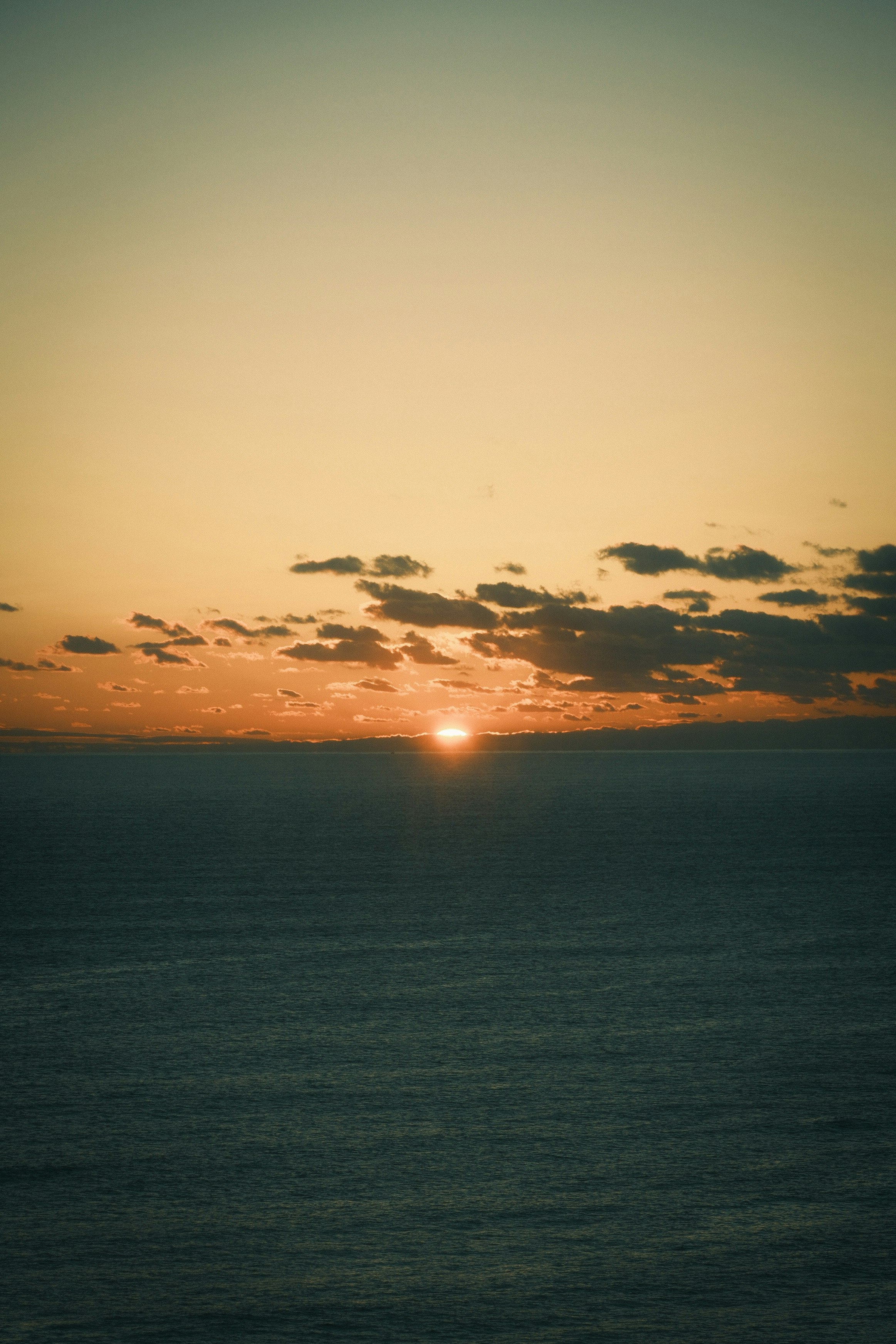 Orange sunset over the ocean horizon with a blue sky