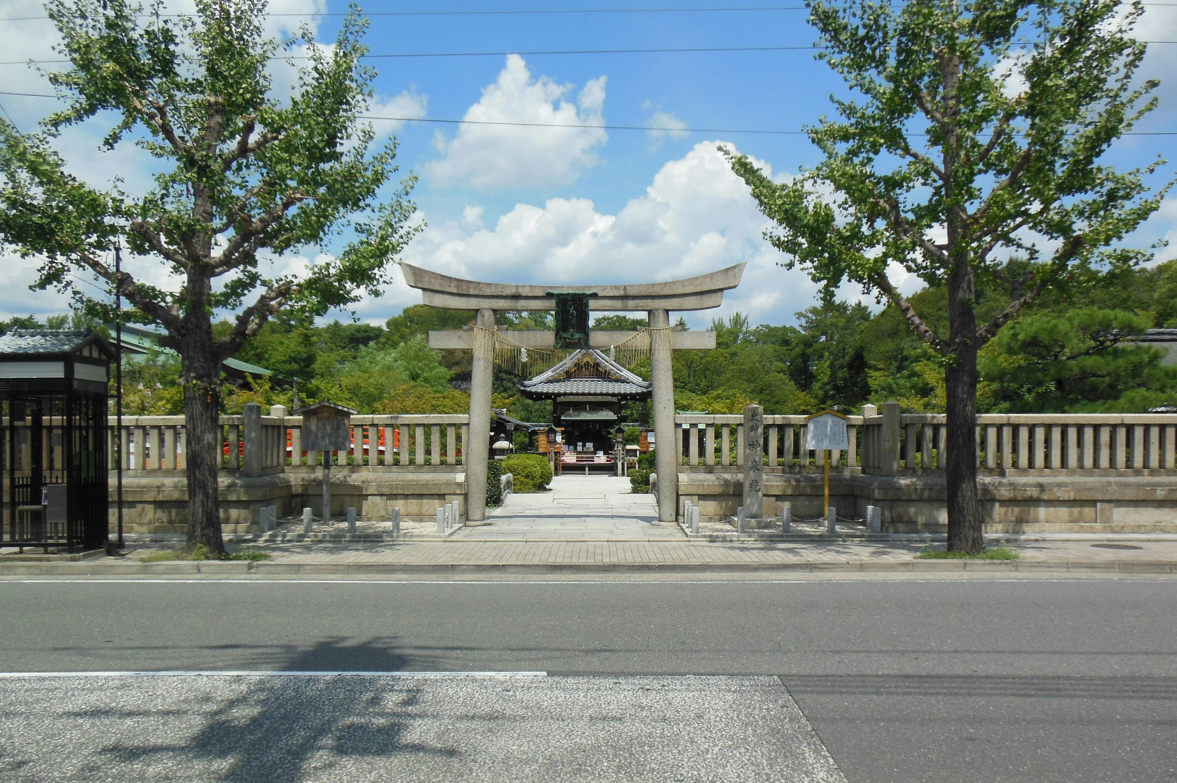 Torii gate of a shrine under blue sky with green trees