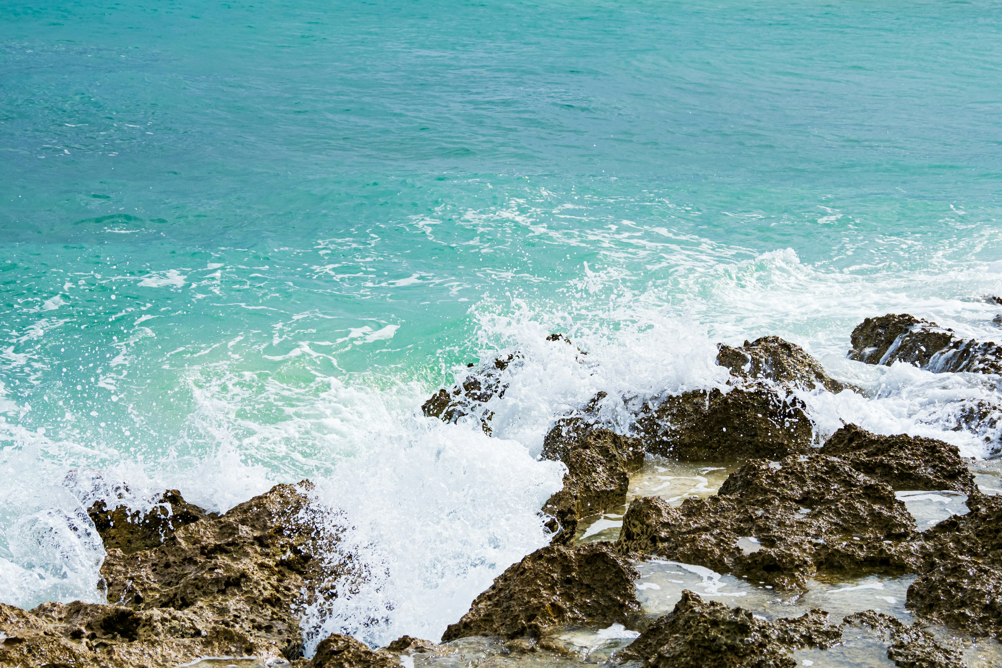 Laut biru dan garis pantai berbatu ombak menghantam batu