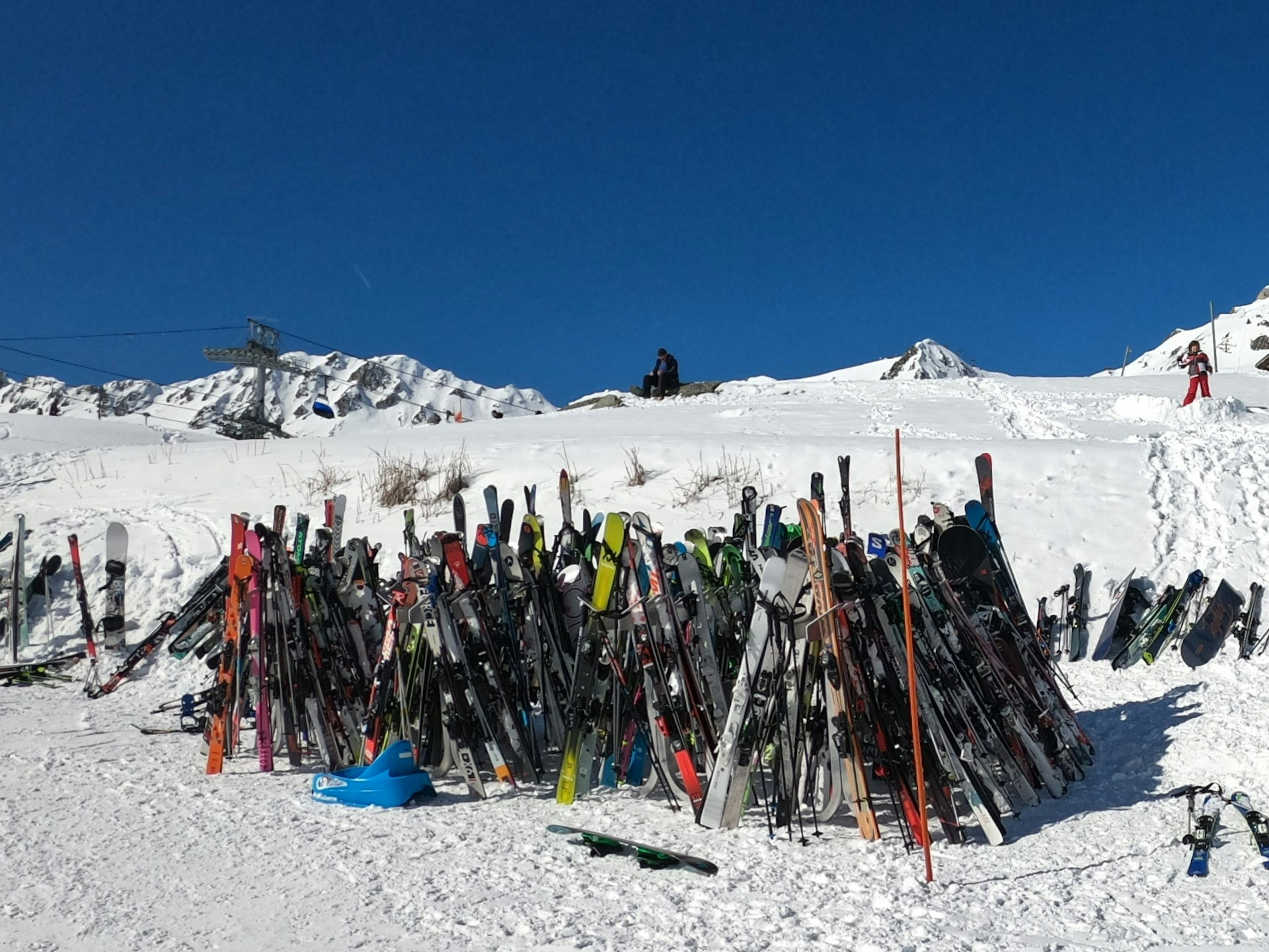 A collection of skis standing in the snow on a mountain