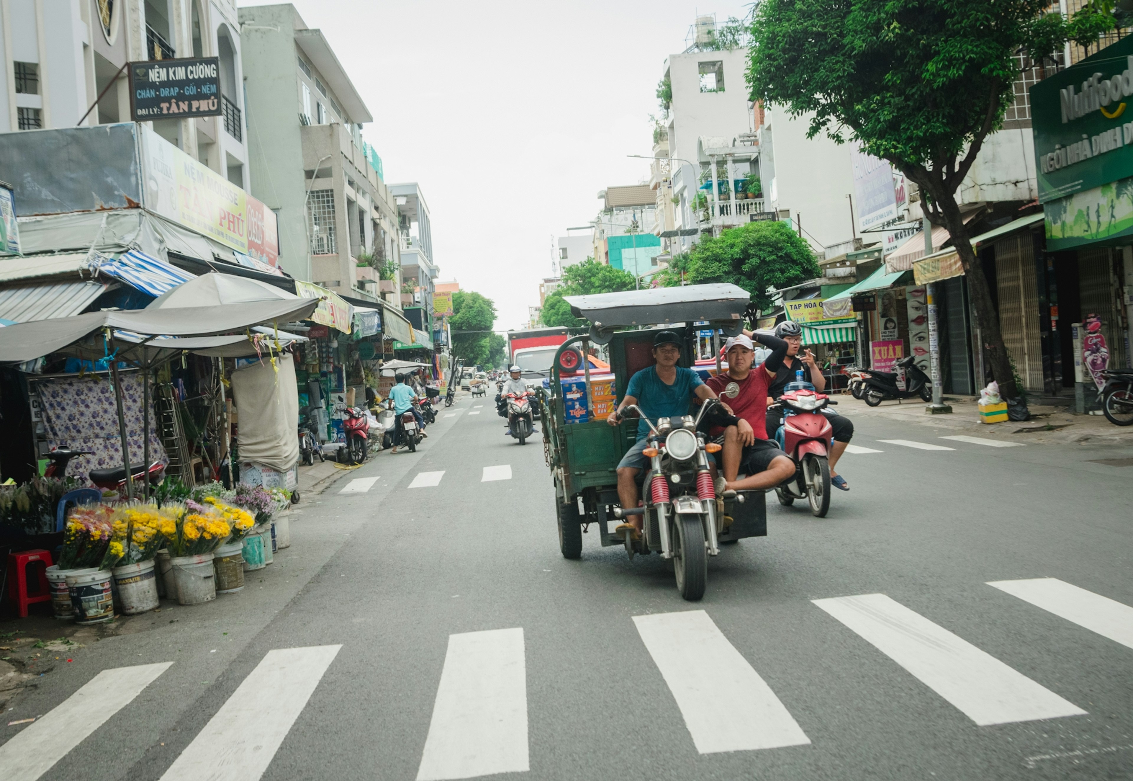 สามล้อบนถนนในเมืองพร้อมพ่อค้าและคนเดินถนน