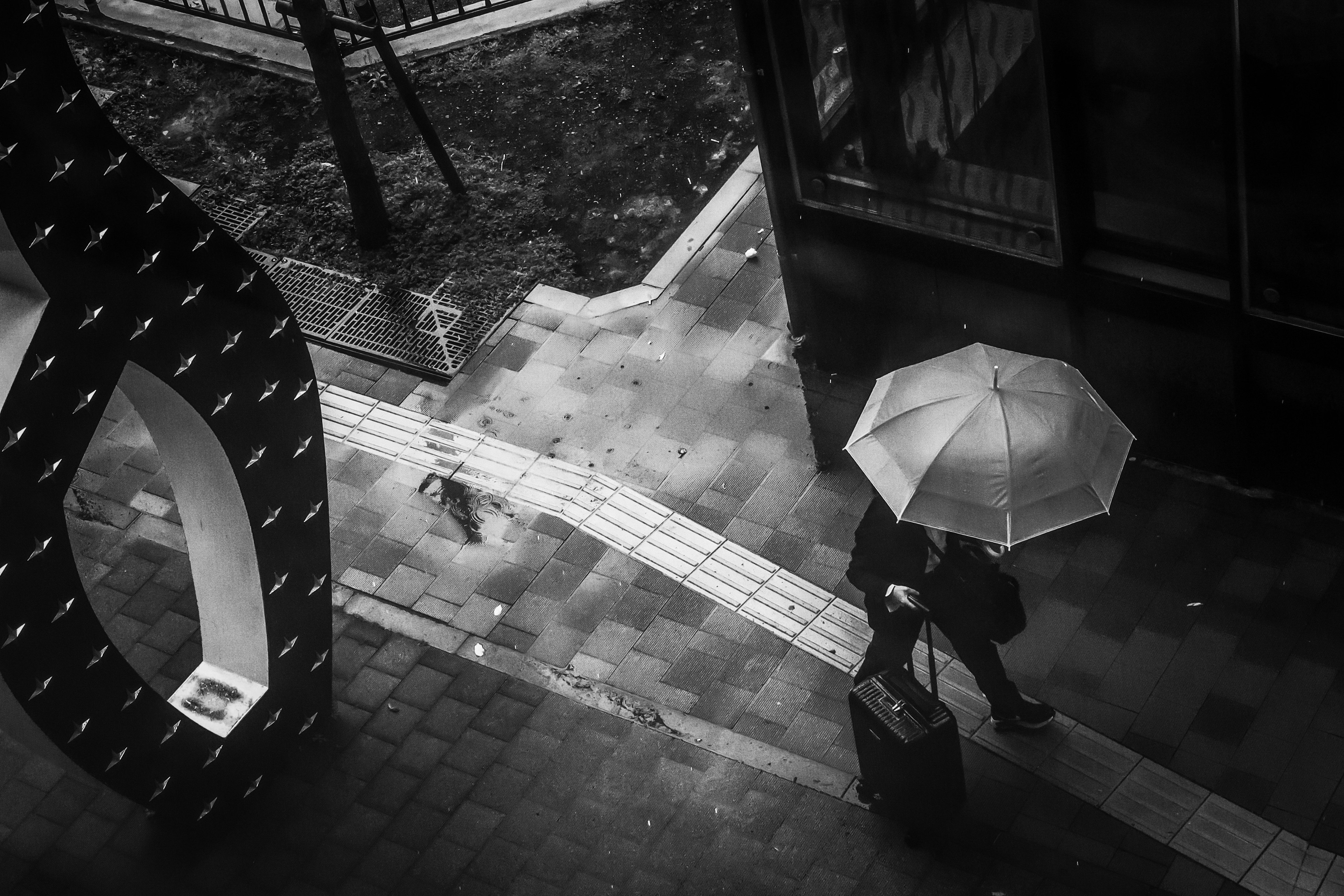 A businessman with an umbrella walking in a black and white urban scene