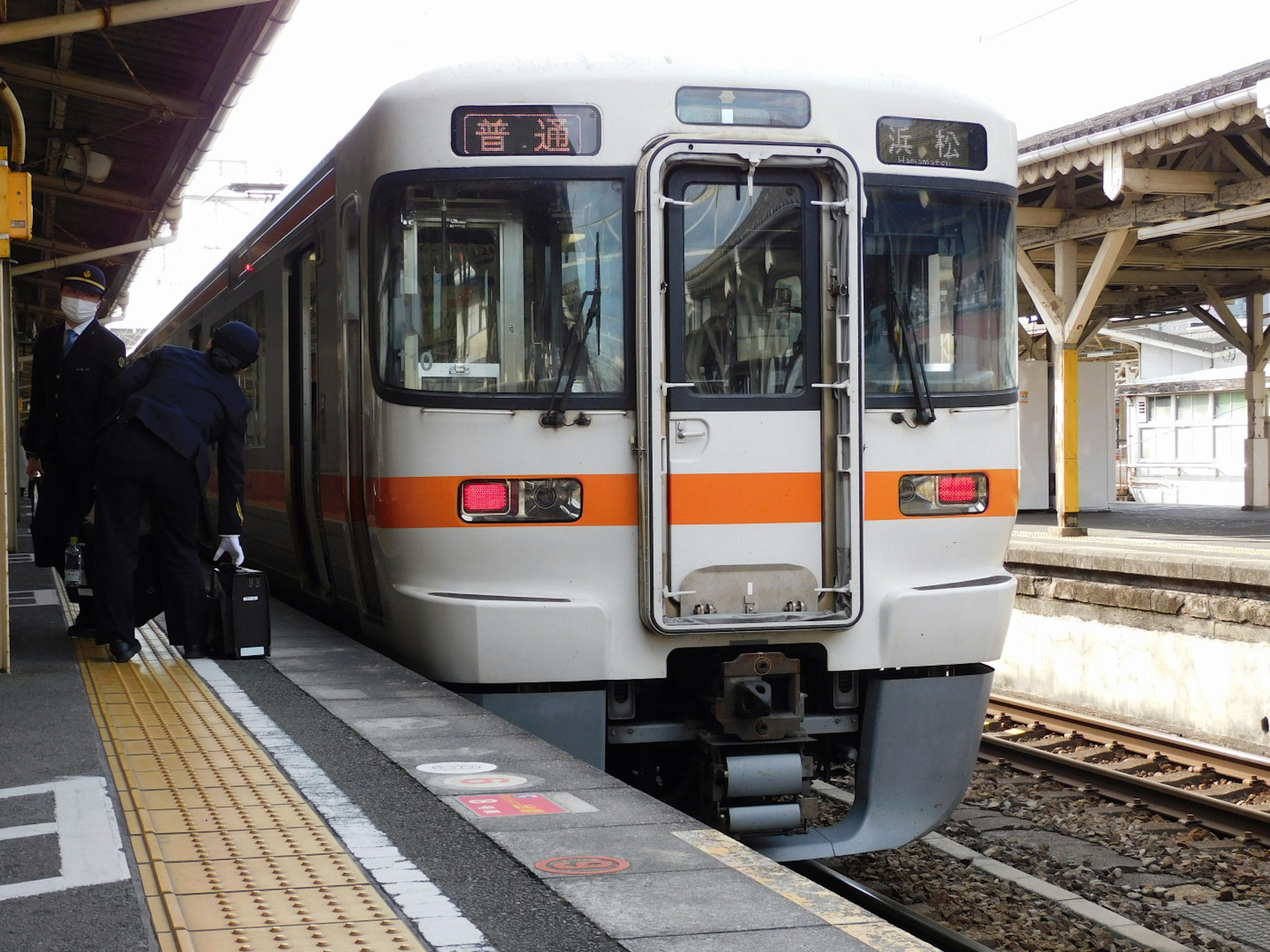 Japanischer Zug mit orangefarbenen Streifen an einem Bahnhof