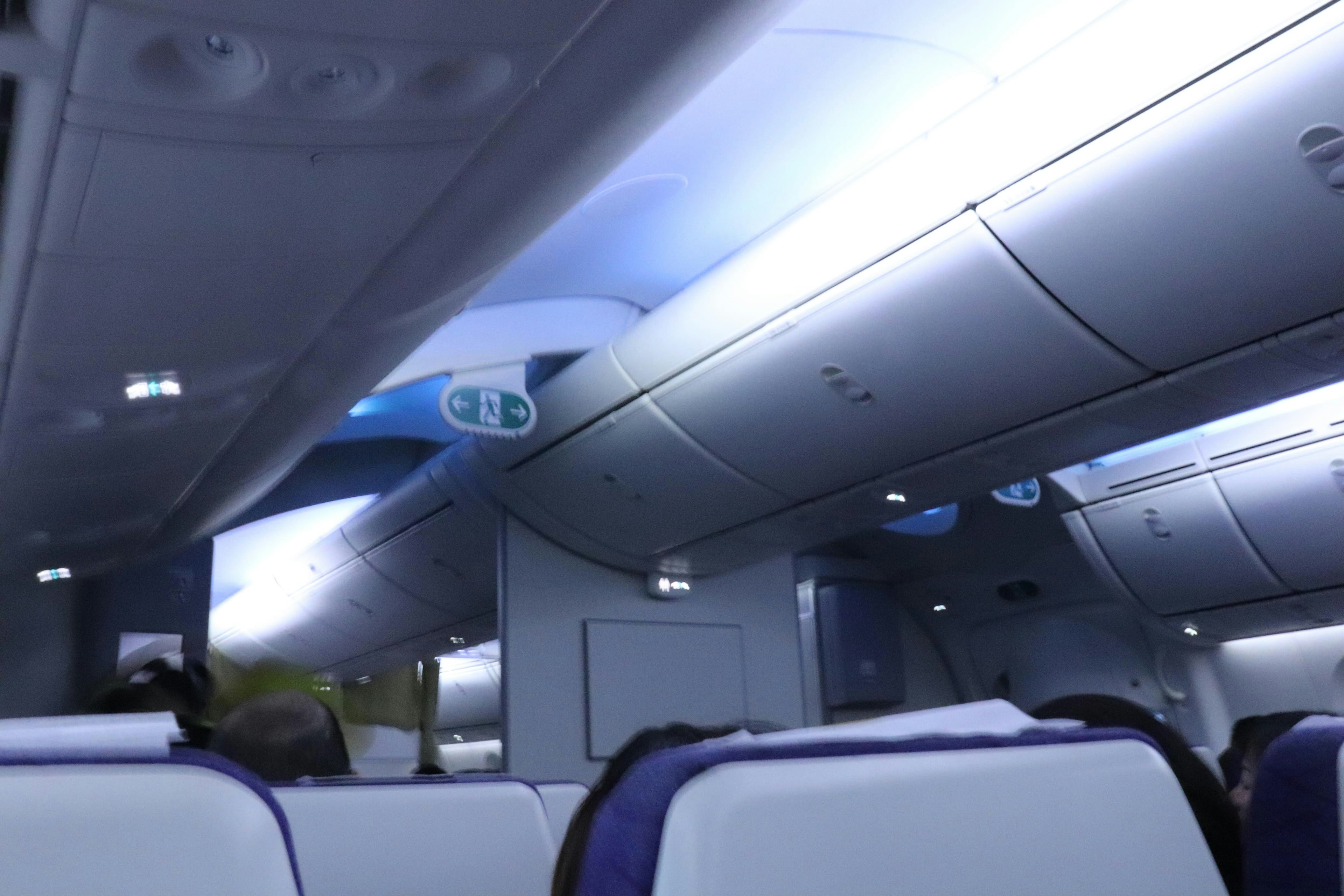 Interior de un avión con luz azul y asientos blancos