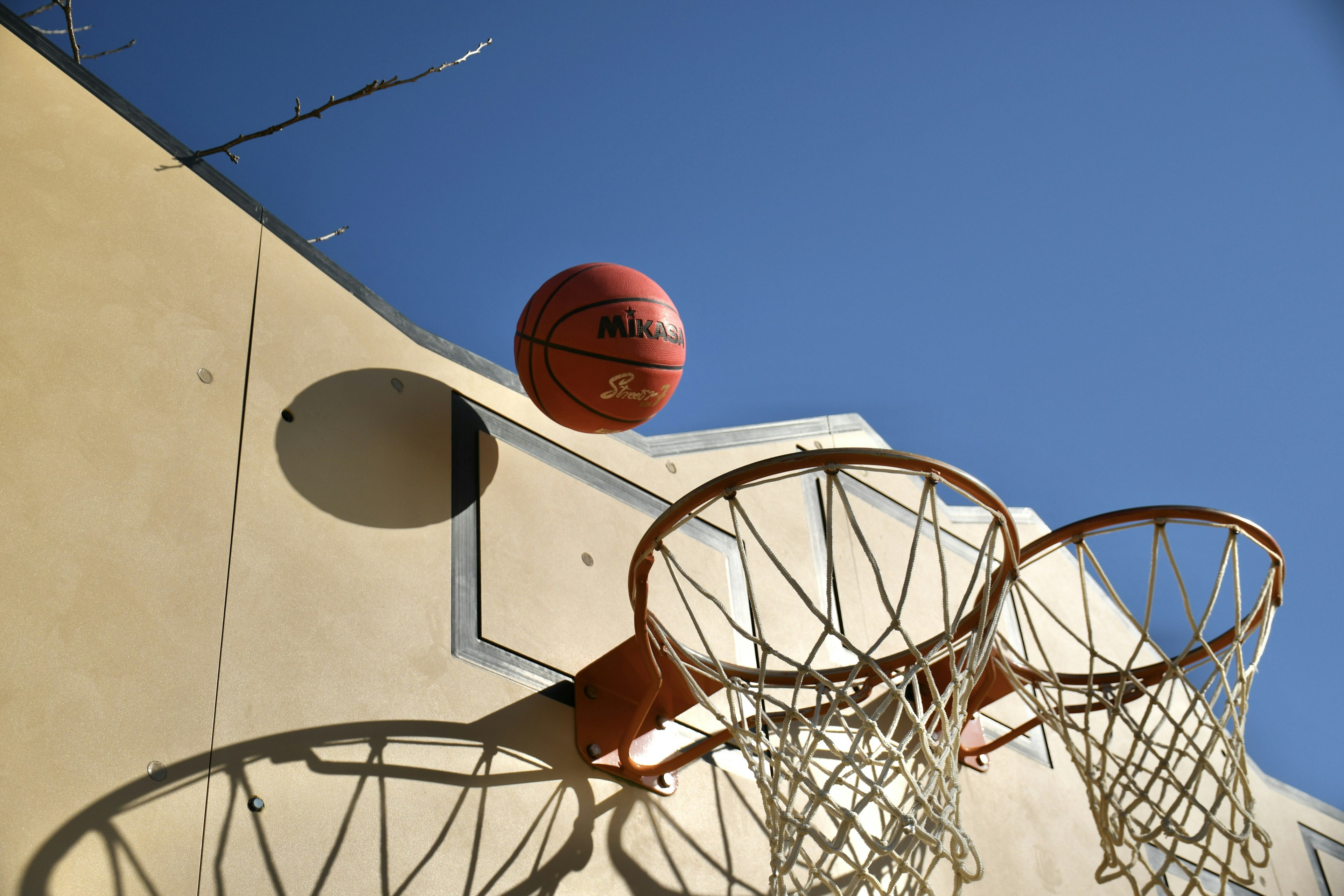 Ein Basketball, der unter einem klaren blauen Himmel auf den Korb zugeht