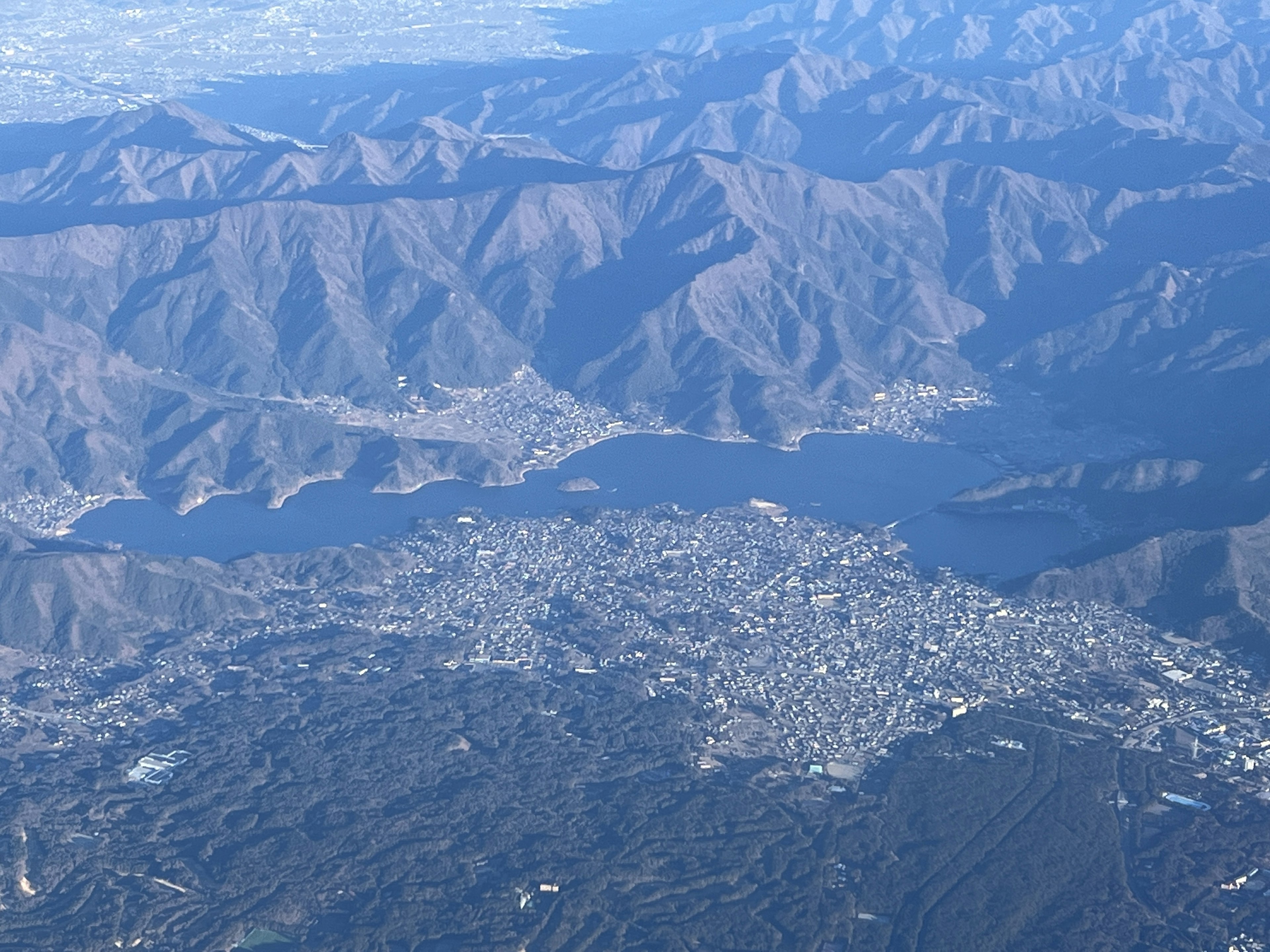 Vista aérea de montañas y un lago con una ciudad