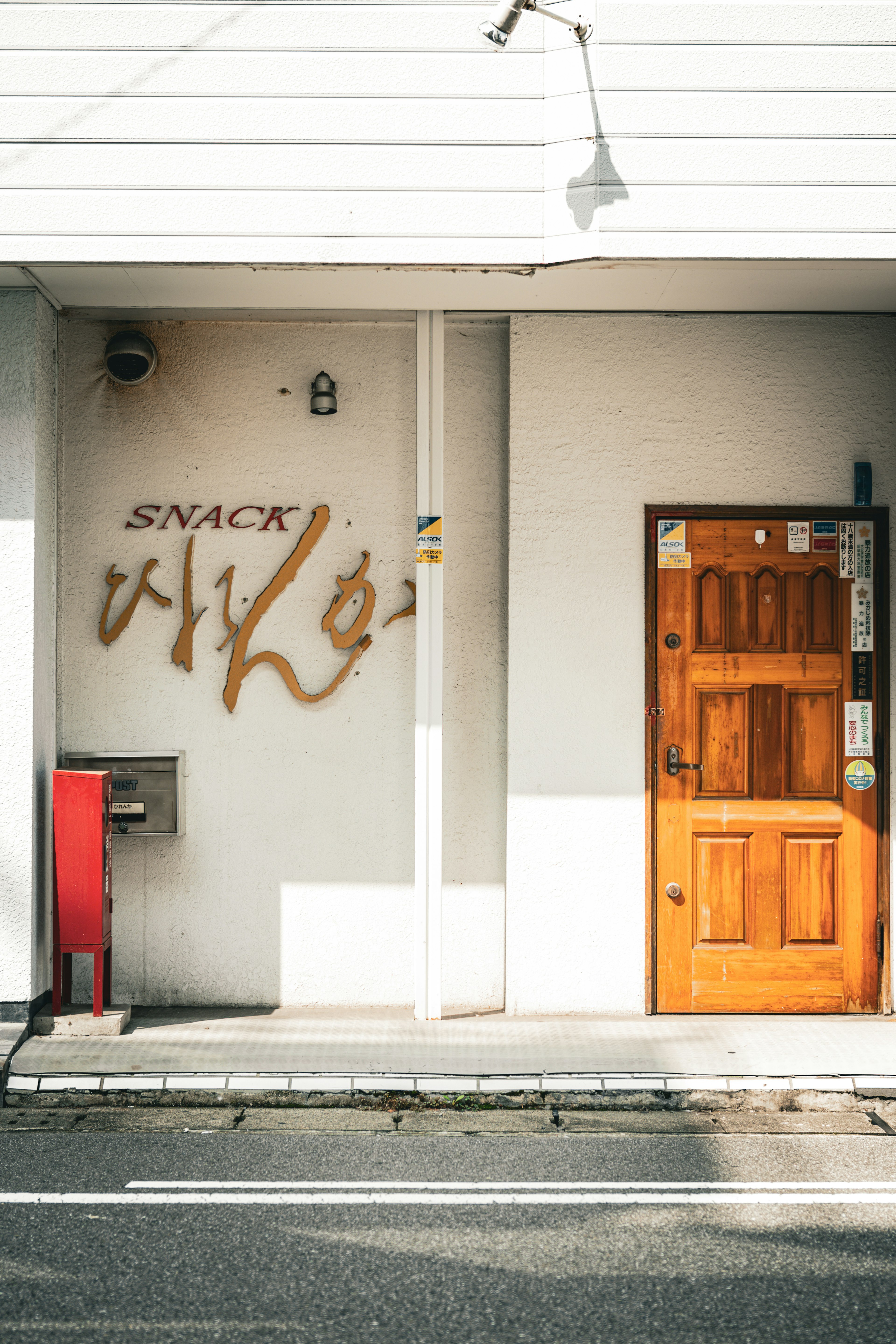 Exterior view of a snack shop with a wooden door and sign