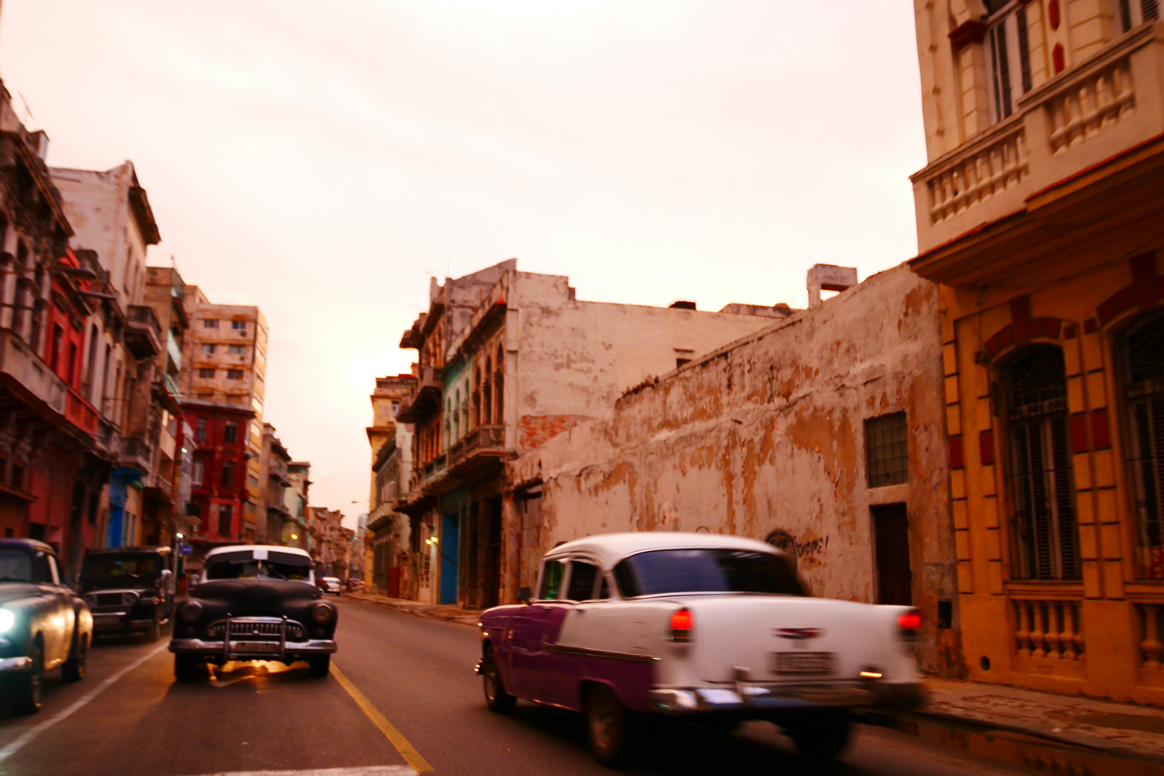 Scena di strada cubana con auto d'epoca e edifici colorati